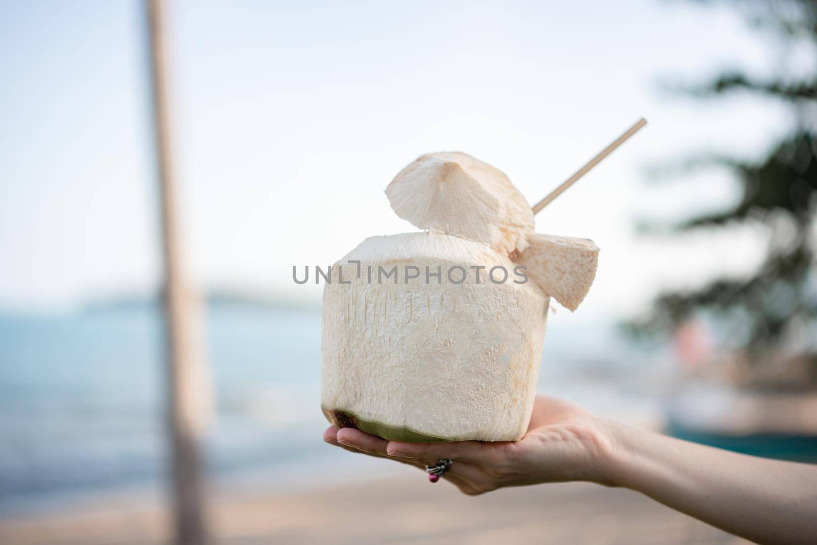 Fresh coconut cocktail in hand over ocean background.