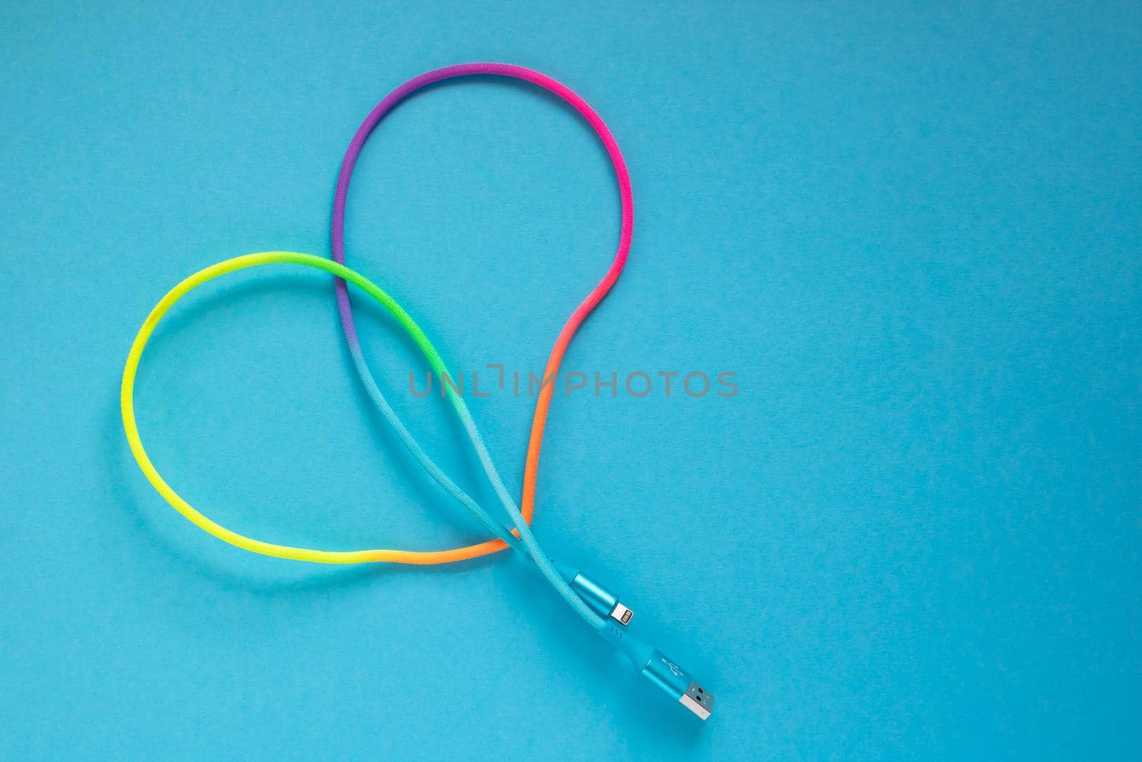 Multicolored rainbow USB cable for a smartphone on a blue background