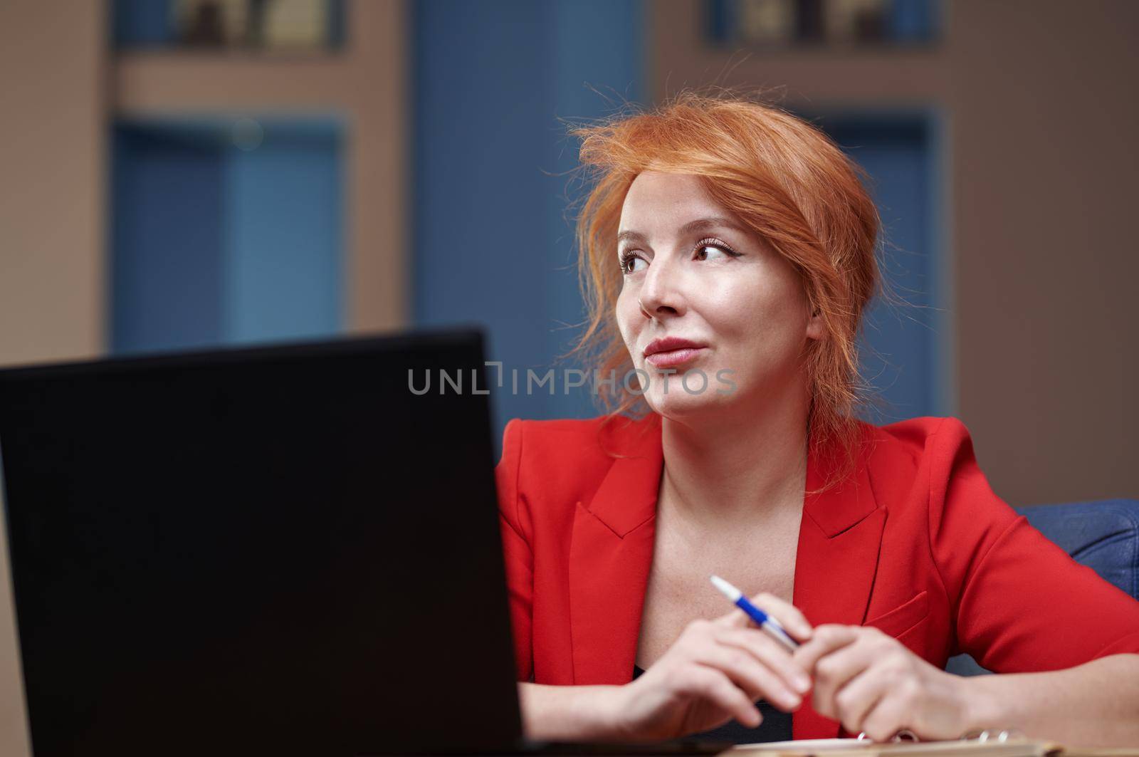 Pensive businesswoman at the office working on laptop by Novic