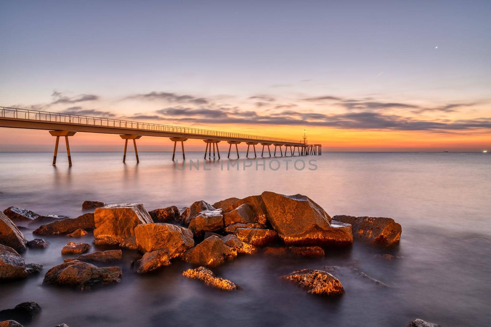 The sea pier of Badalona in Spain with some rocks before sunrise
