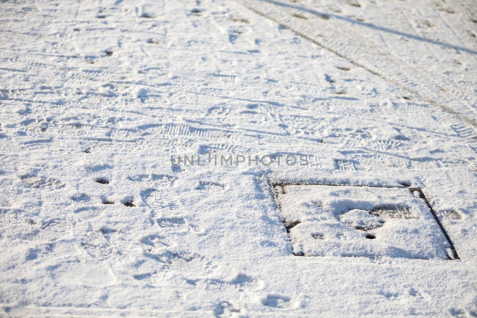 During winter weather, fresh snow lies on a busy sidewalk. Unsnowed city sidewalks.