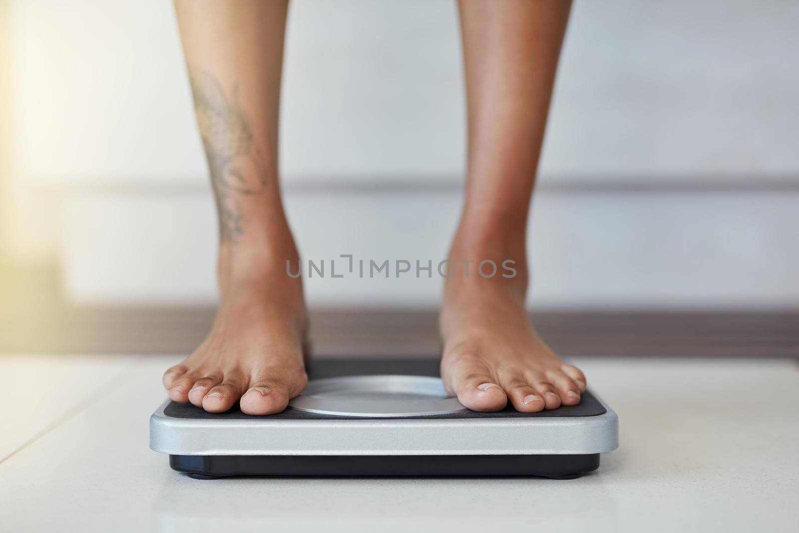 And the results are in. Closeup shot of a woman weighing herself on a scale at home. by YuriArcurs