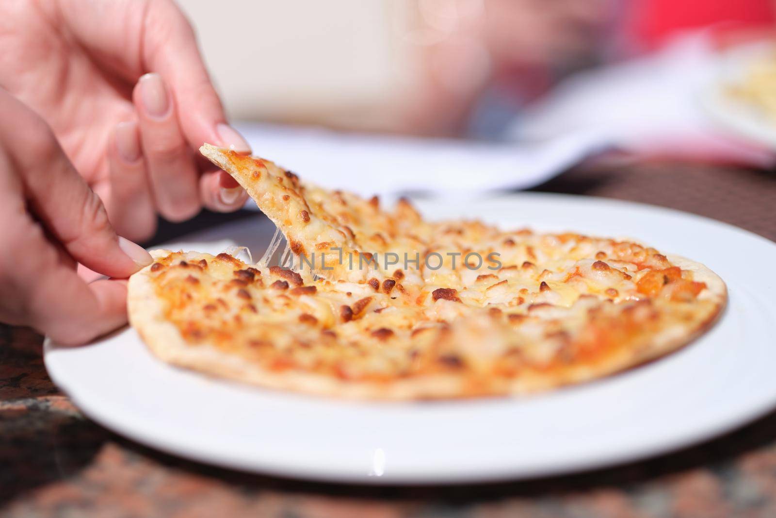 Female hand tearing off appetizing hot slice of pizza with cheese closeup. Street food concept