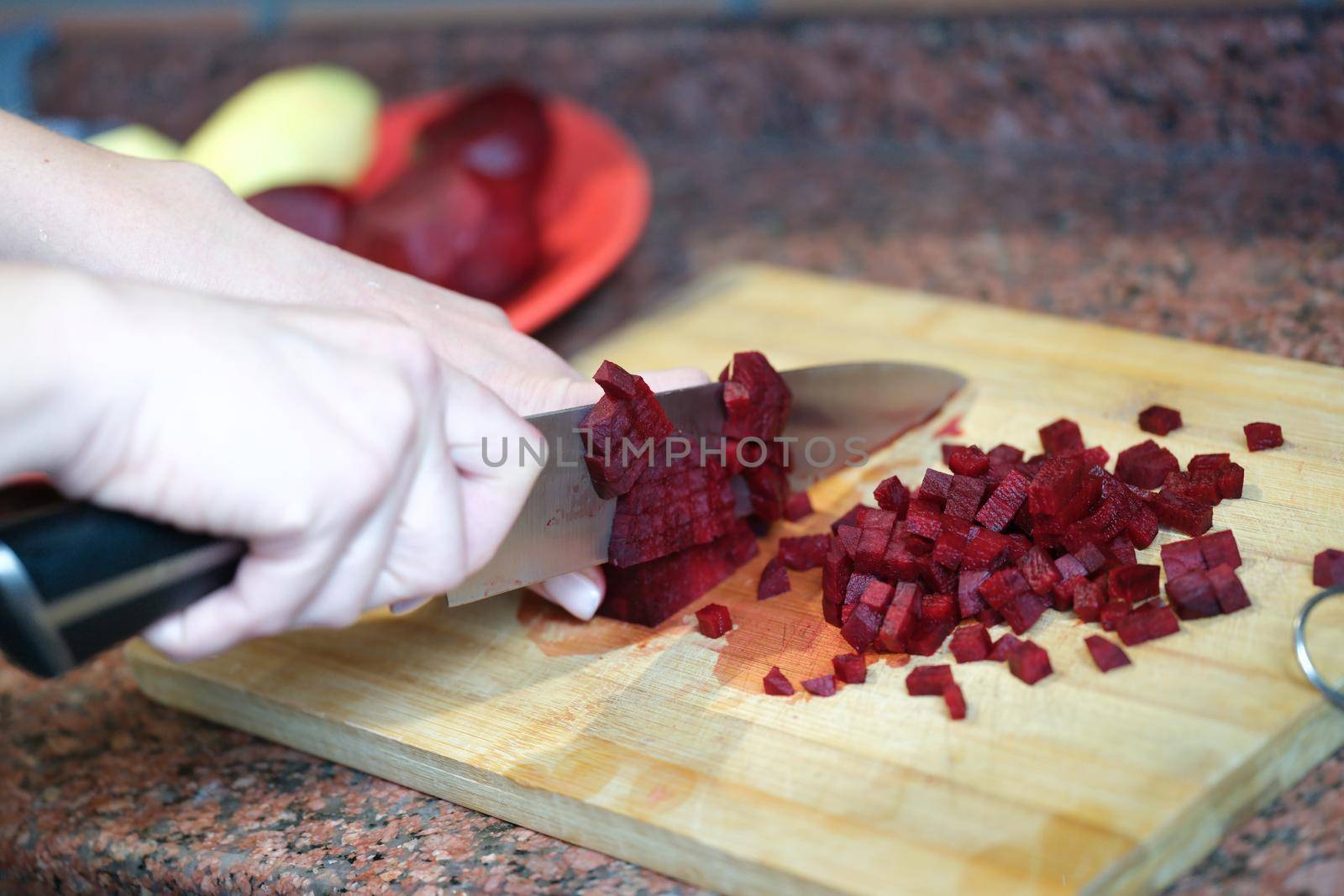 Woman housewife cutting beets into cubes for salad closeup. Healthy food vegetarian cuisine concept