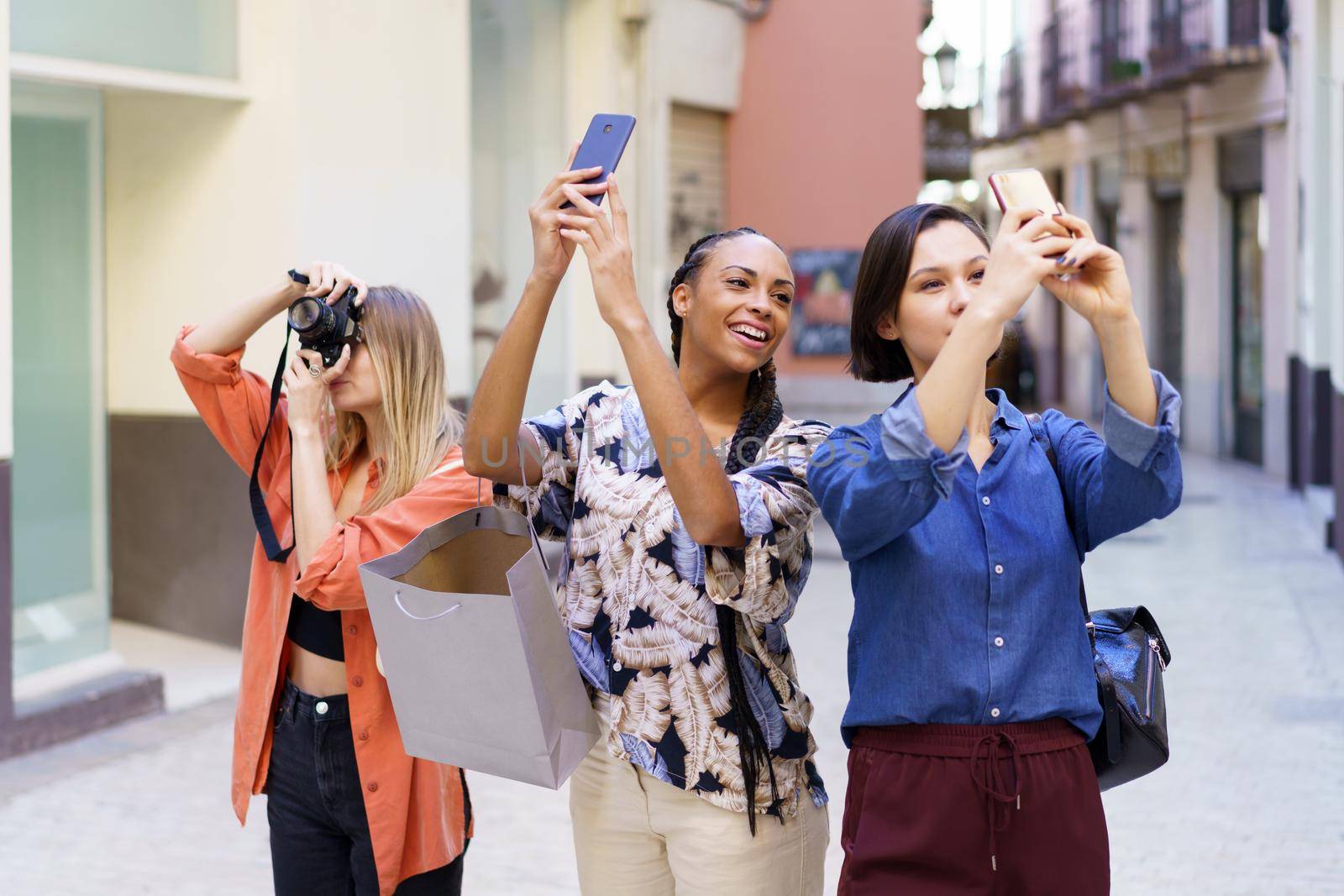 Content multiracial friends taking photos of street by javiindy