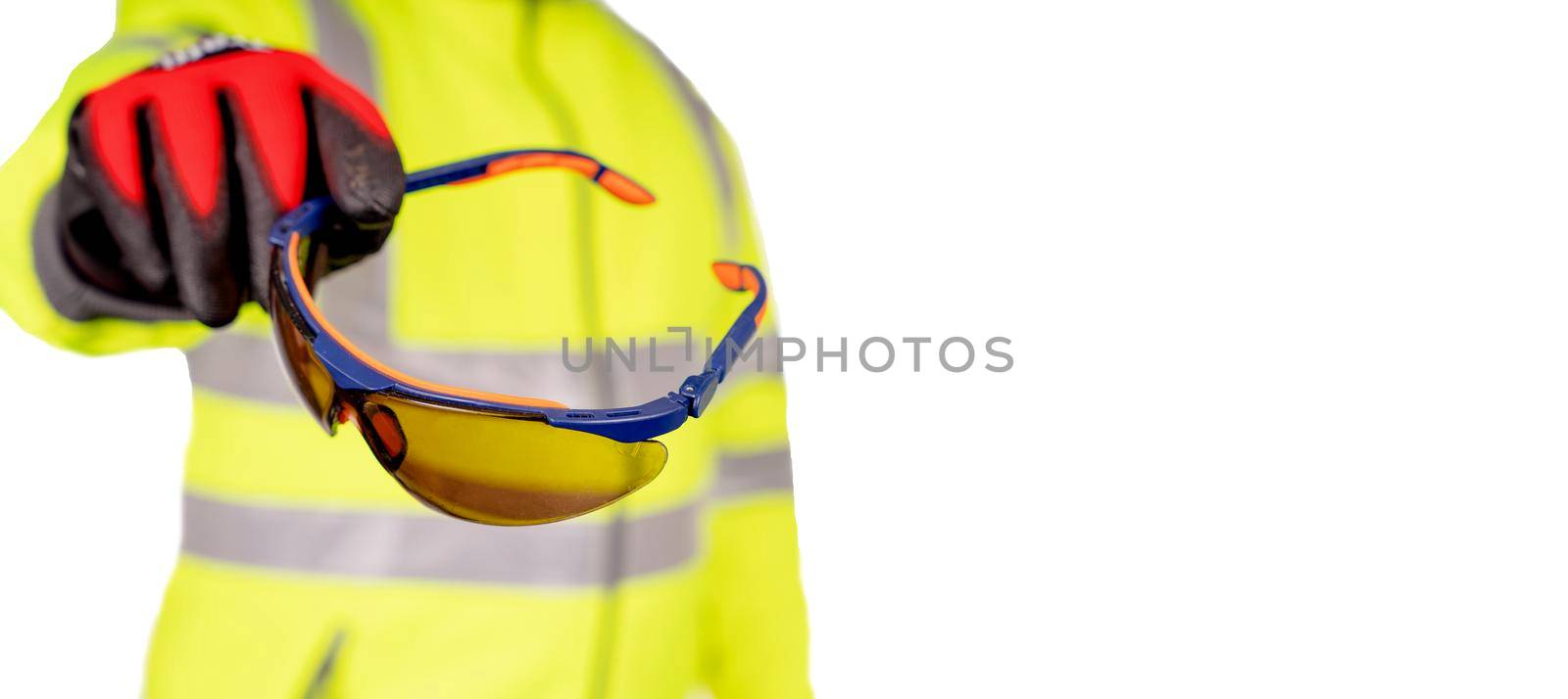 A construction worker in a bright yellow hi-viz coat and red safety gloves giving tinted safety glasses to the viewers for eye protection isolated on white background. Safety on construction site banner concept