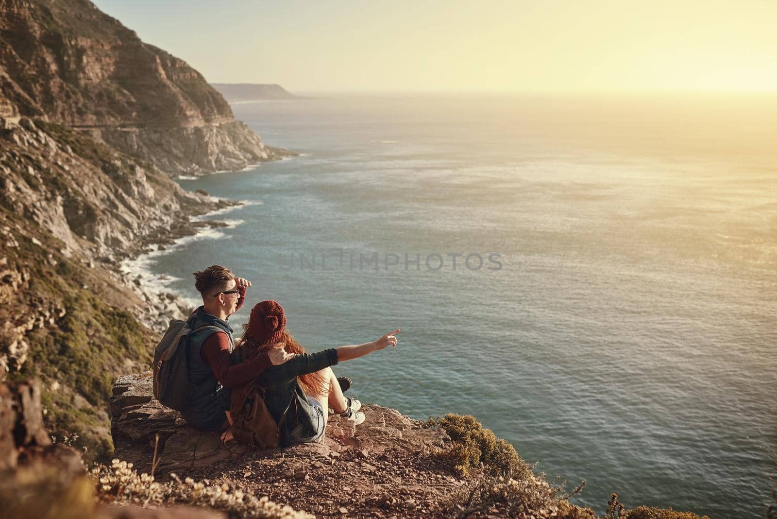 High angle shot of an affectionate young couple taking in the view from a mountaintop.