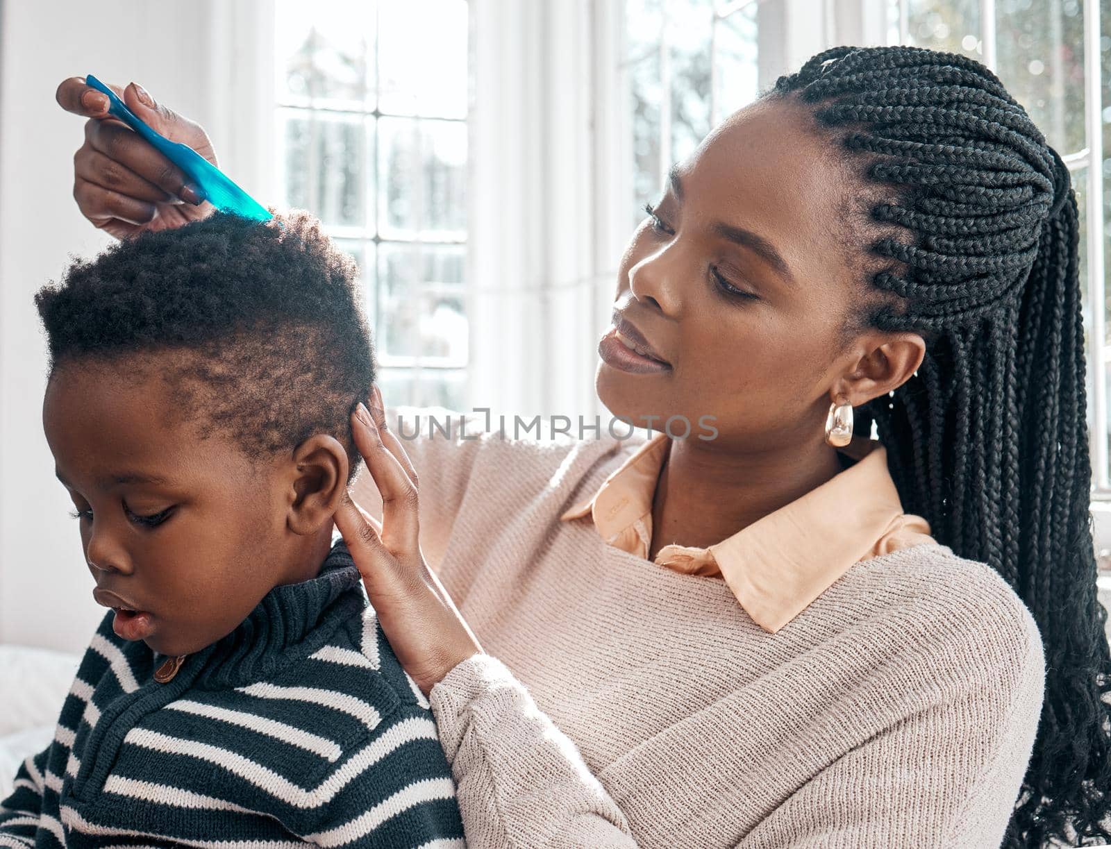 Cropped shot of an attractive young woman combing her sons hair while sitting on a bed at home.