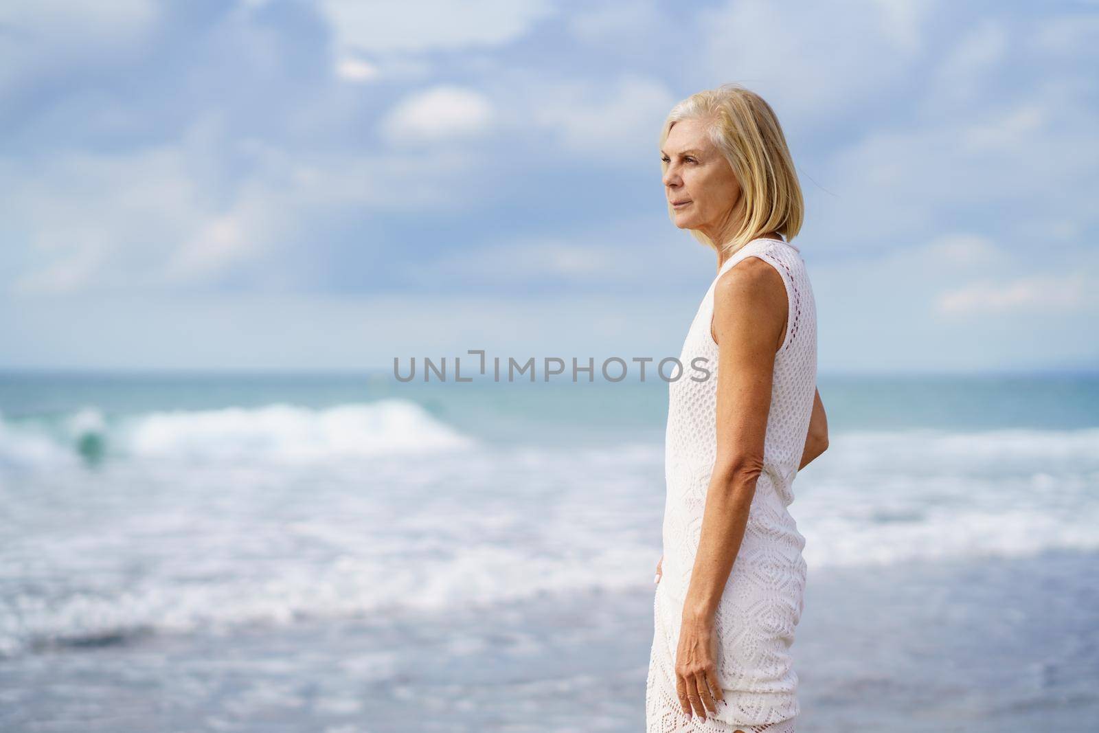 Mature woman gazing serenely at the sea. Elderly female enjoying her retirement at a seaside location.