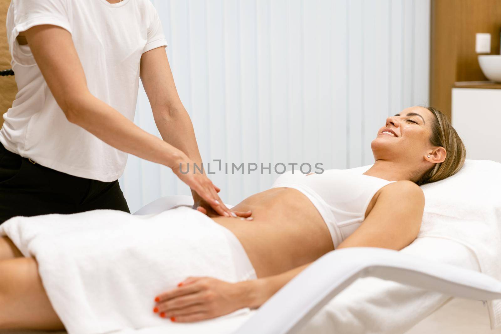 Middle-aged woman having a belly massage in a beauty salon. by javiindy