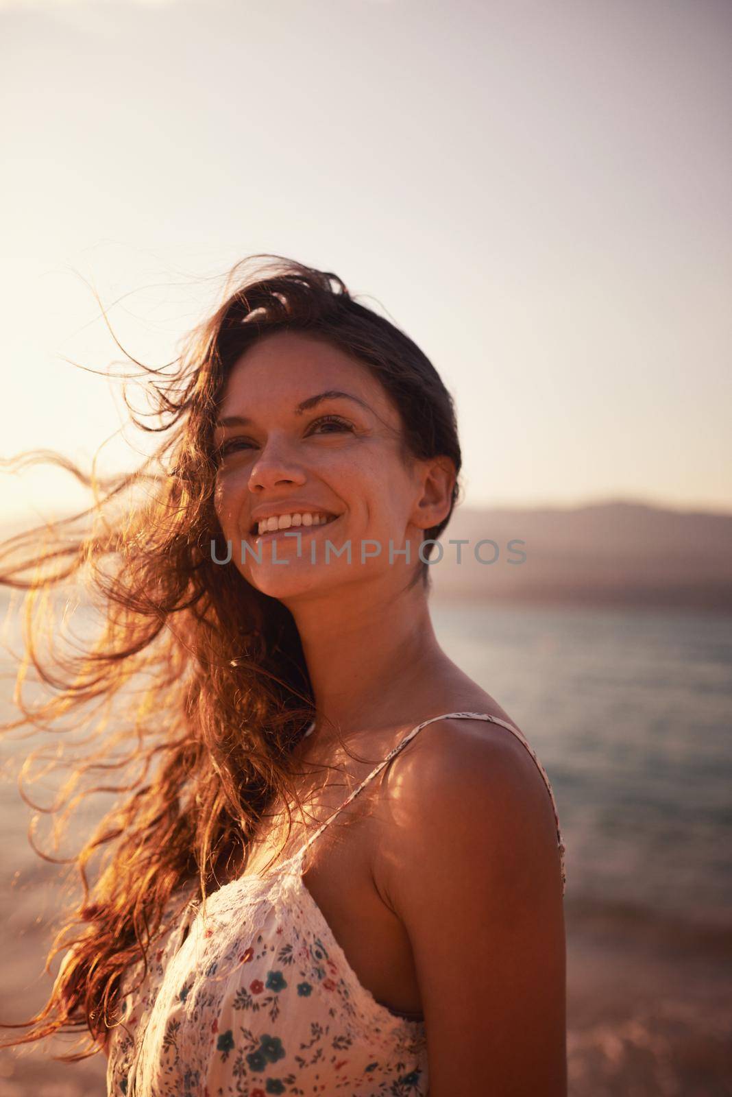 Enjoying the sea air. Cropped shot of a beautiful young woman on the beach. by YuriArcurs