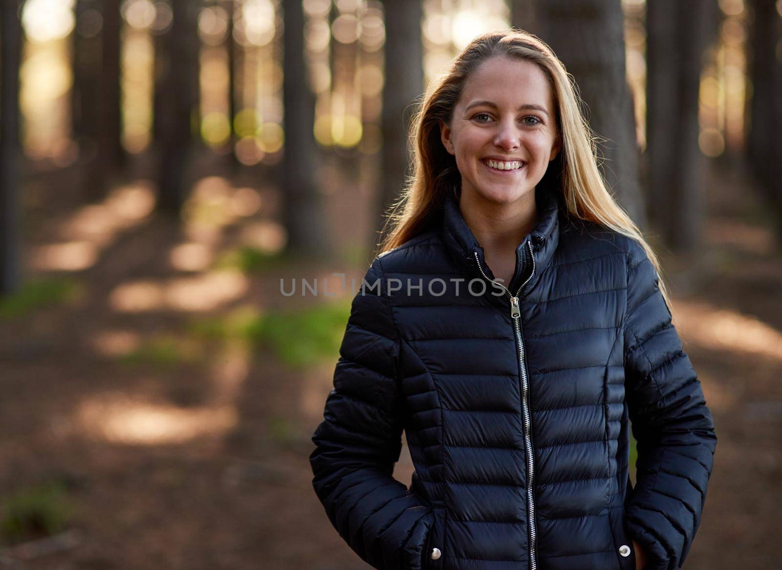 Portrait of a happy young woman exploring a forest on her own.