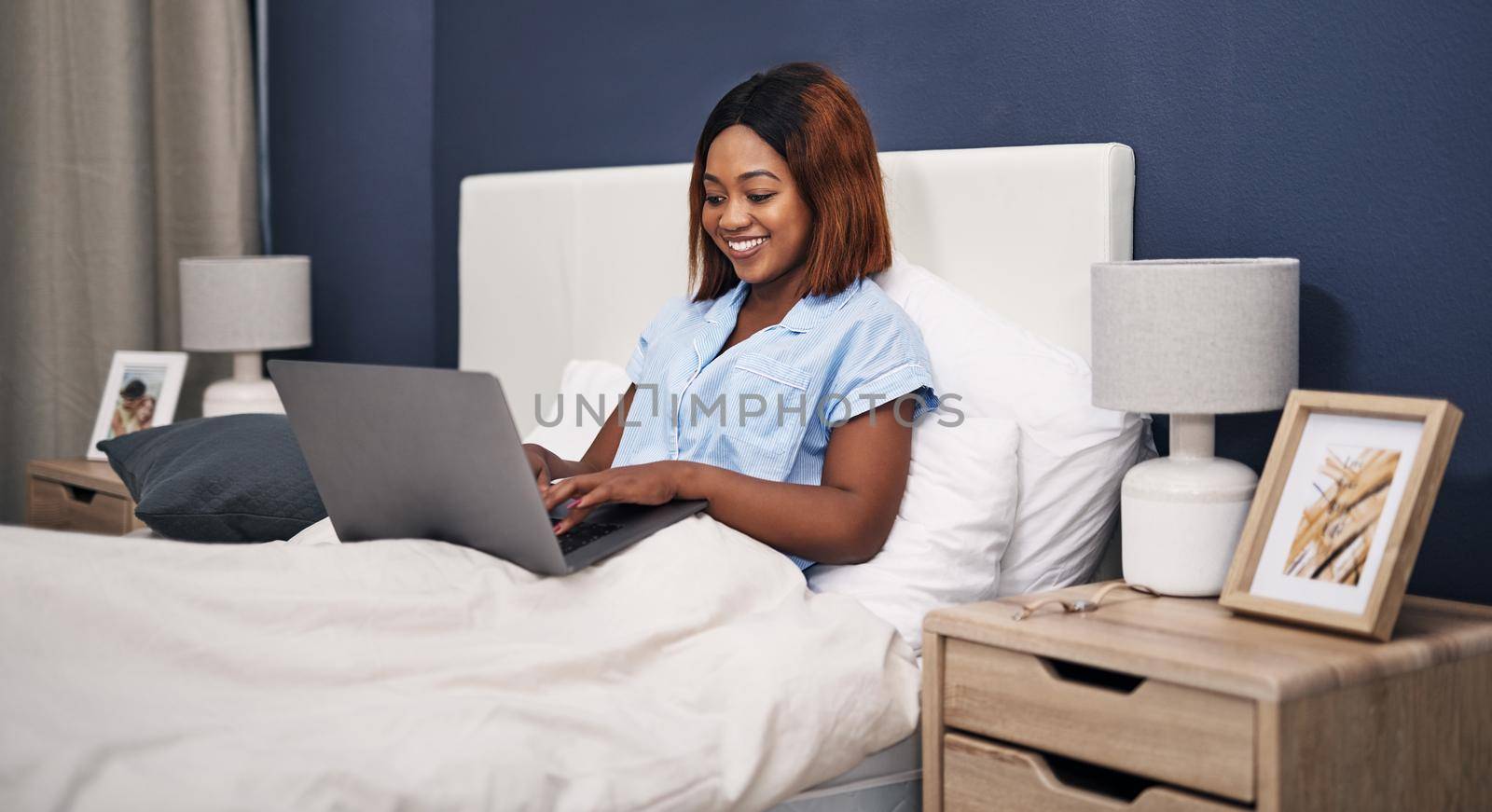 Cropped shot of an attractive young woman using her laptop while sitting in bed.