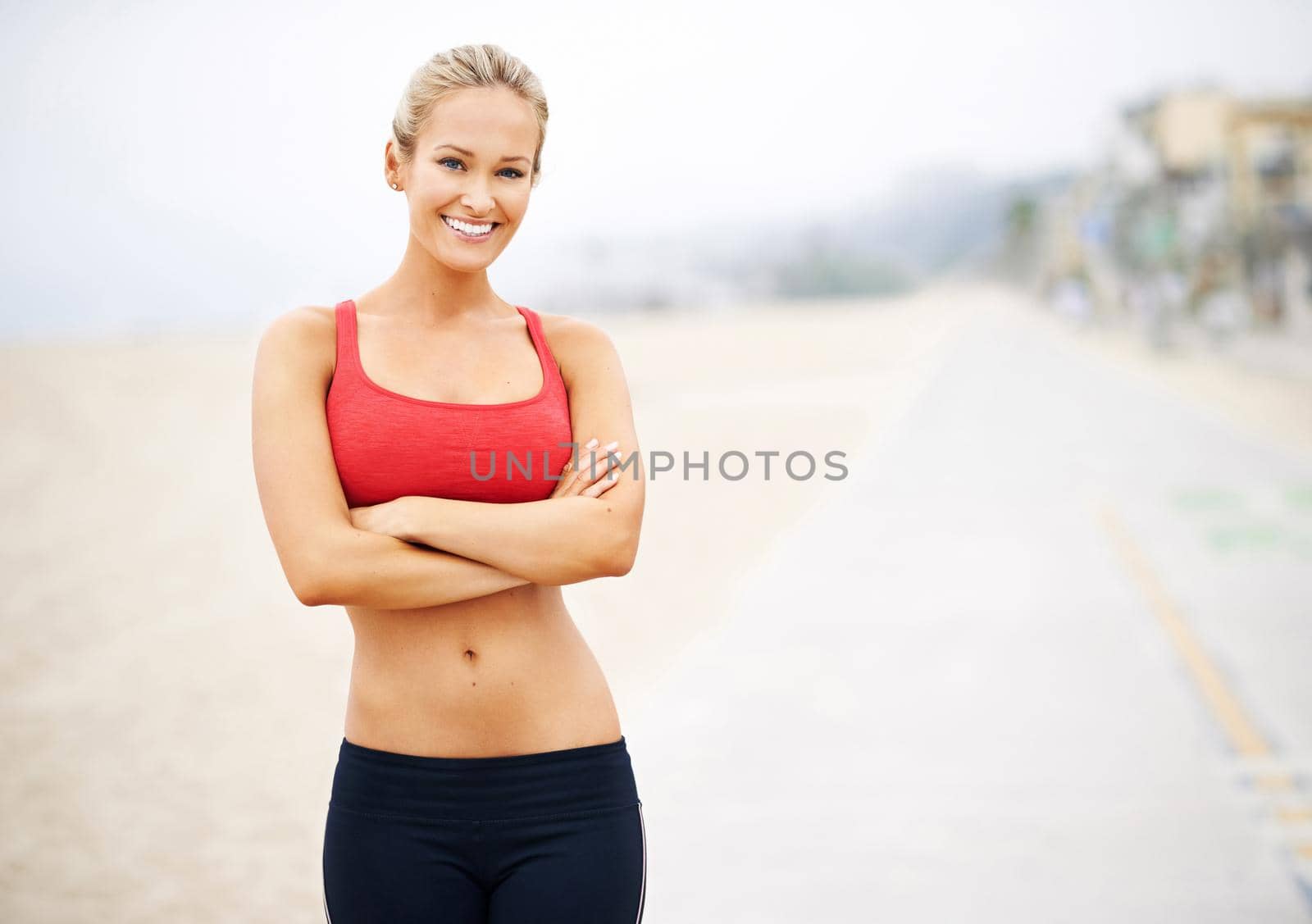 Portrait of a young woman in sportswear standing at the beach.