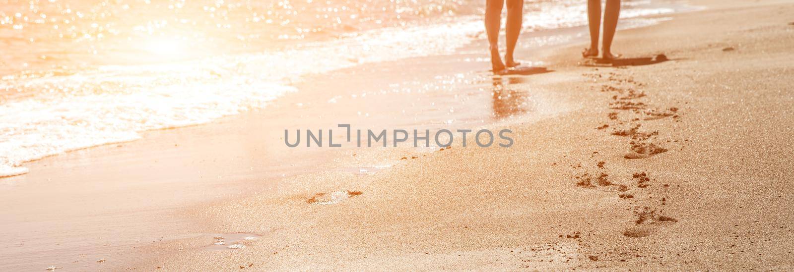 Beach, wave and women footprints at sunset time with sun flare by Mariakray