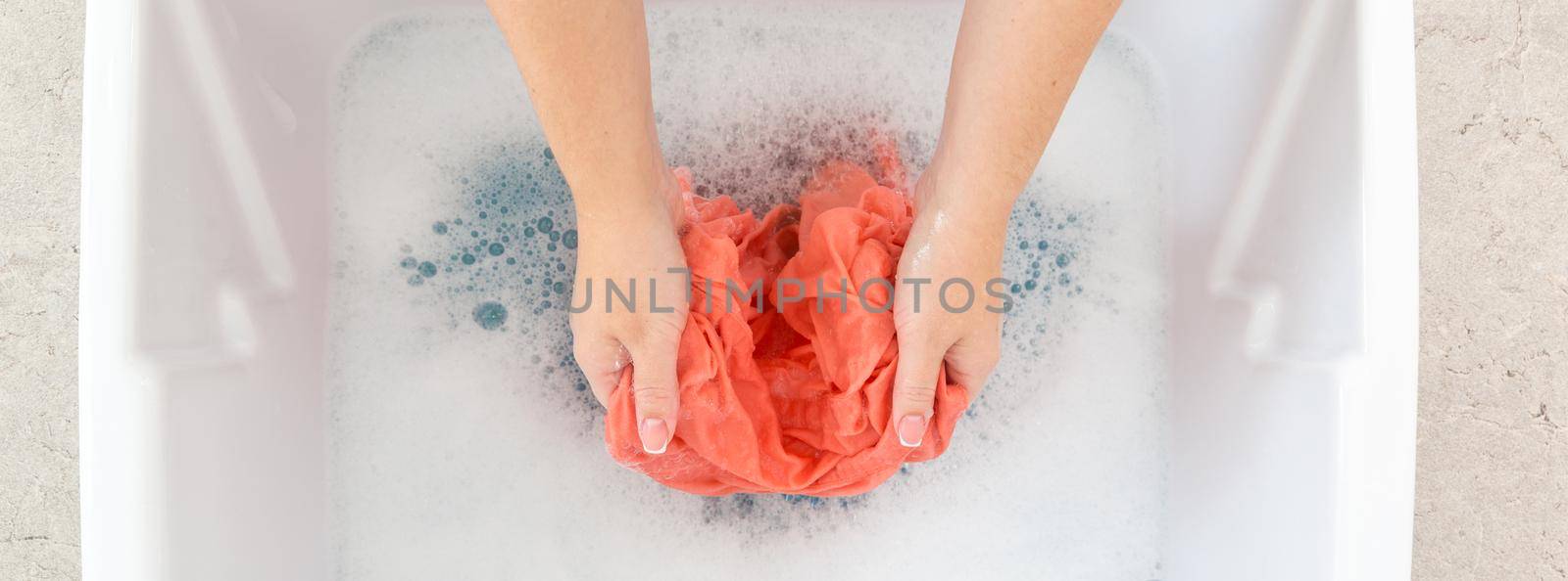 Female hands washing clothes in sink in laundry room