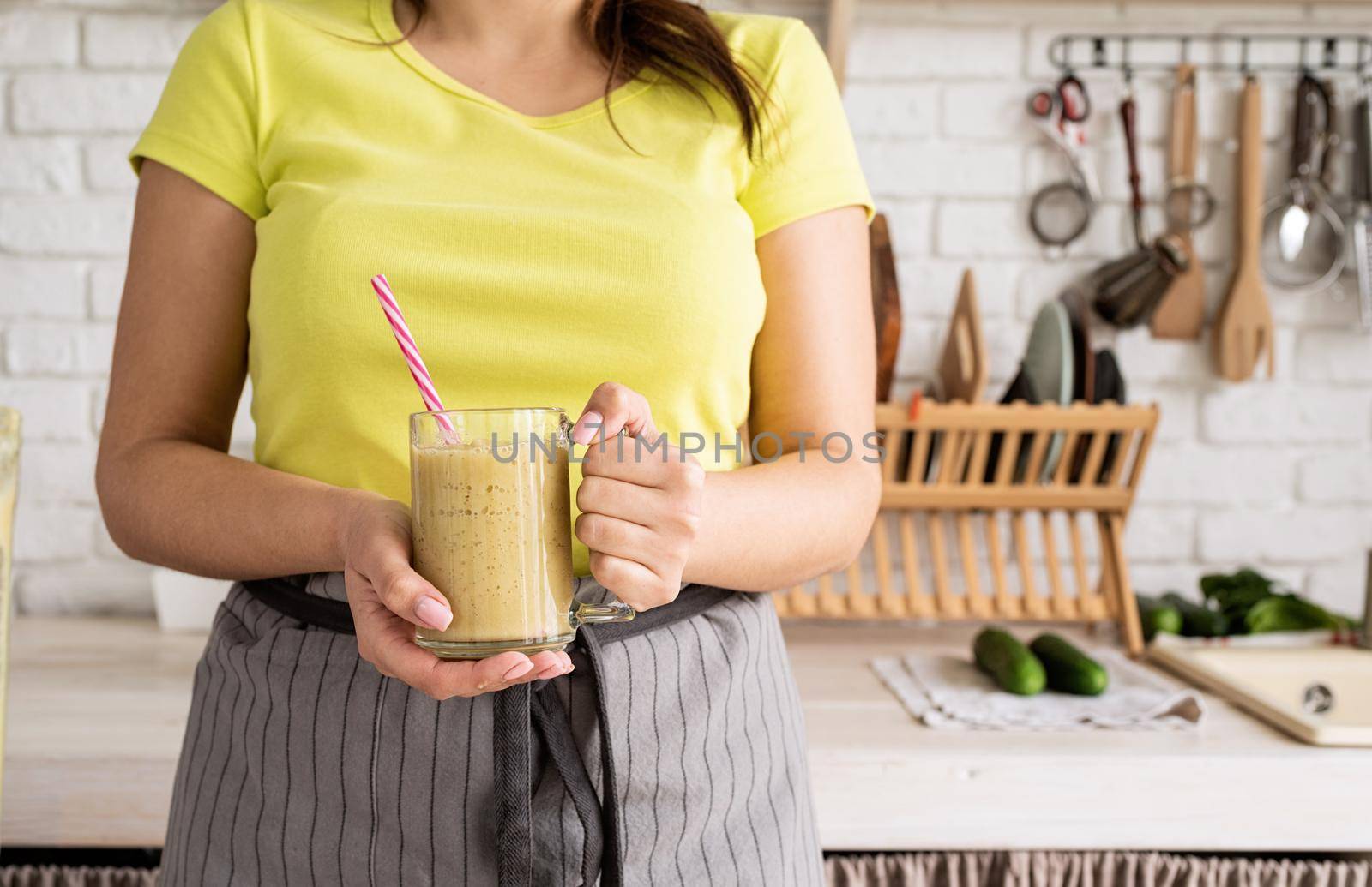 Healthy eating, dieting concept. Young brunette woman drinking fruit banana smoothie at home kitchen from mason jar