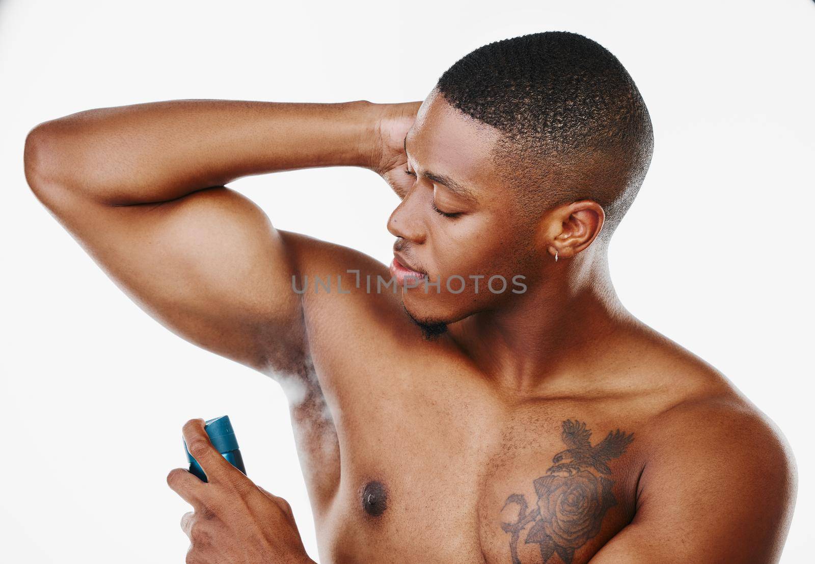 How should a man smell. Studio shot of a handsome young man applying deodorant against a white background. by YuriArcurs