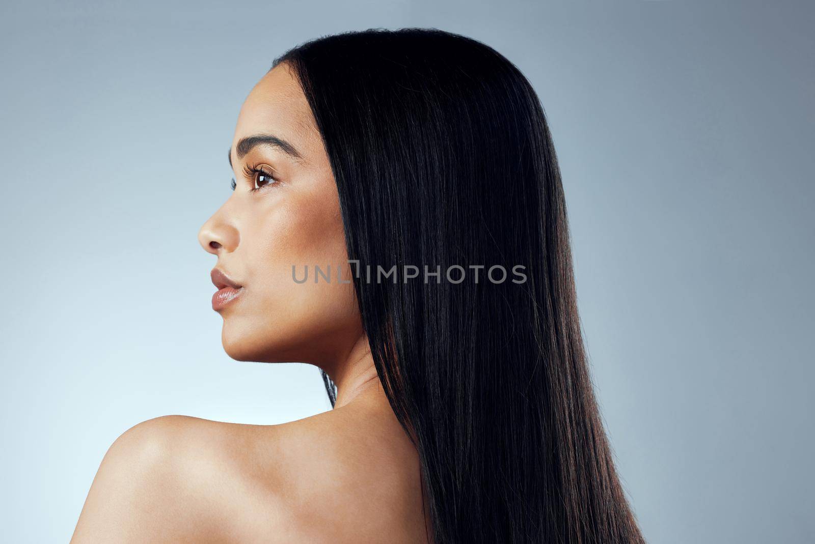 A great hairstyle is the best accessory. Studio shot of an attractive young woman posing against a grey background. by YuriArcurs