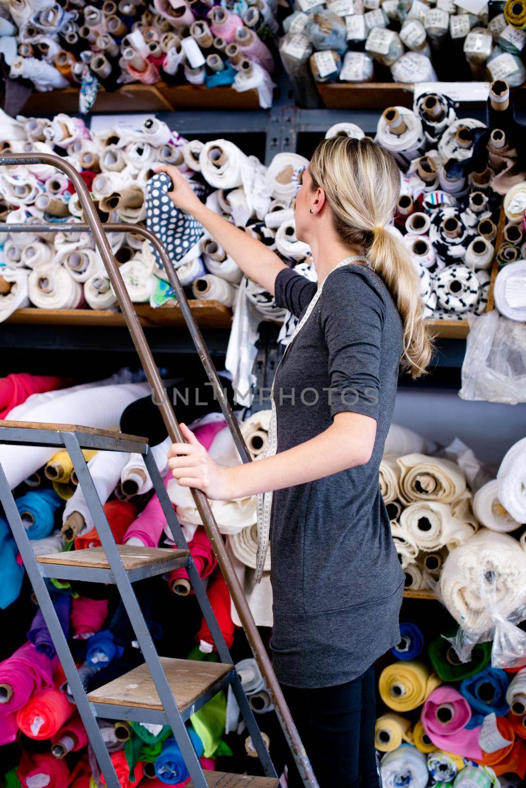 A female store assistant selecting a suitable material from a shelf.