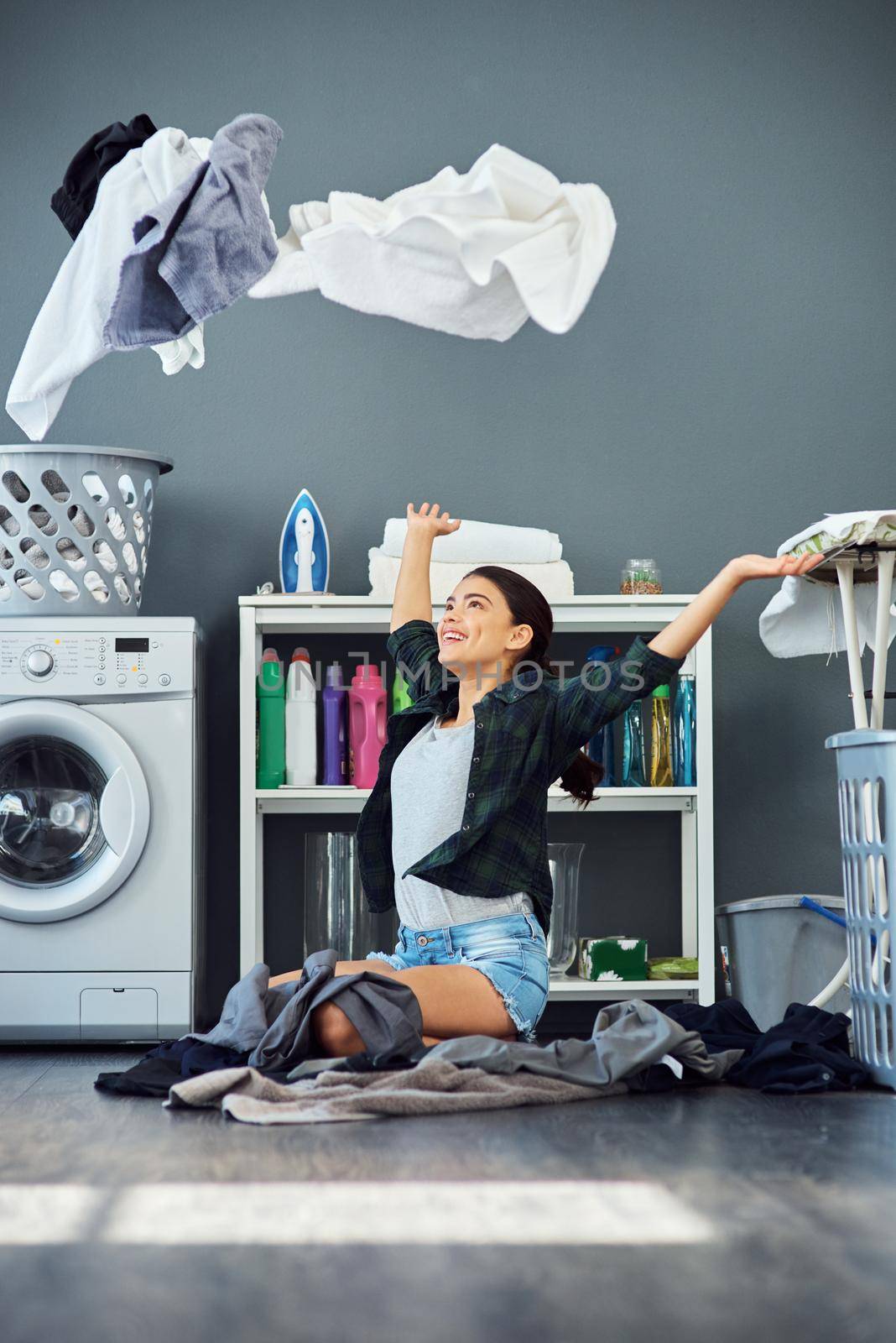 Full length shot of an attractive young woman throwing her washing in the air while doing laundry at home.