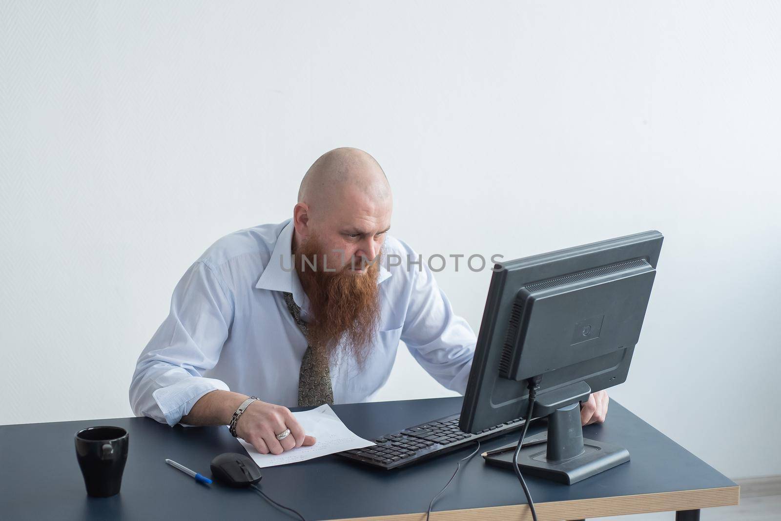 Problems for the office worker. A bald man in a white shirt sits at a desk with a computer and is stressed because of failure. A nervous breakdown