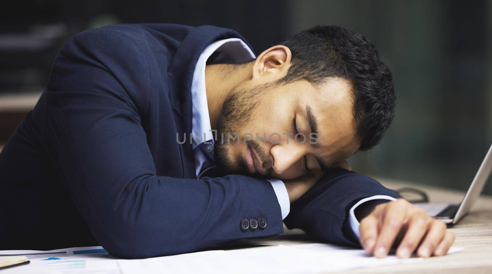 Ive finally hit a wall. Shot of a male stock broker having a nap at his desk. by YuriArcurs