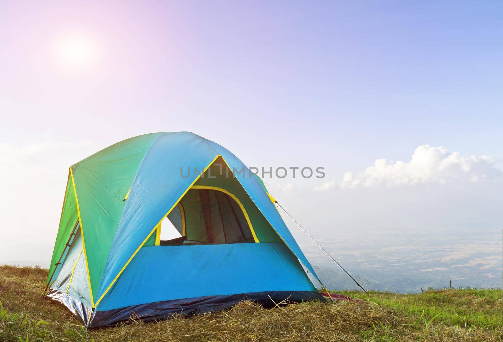 Tent on a grass under in morning sunrise and blue sky