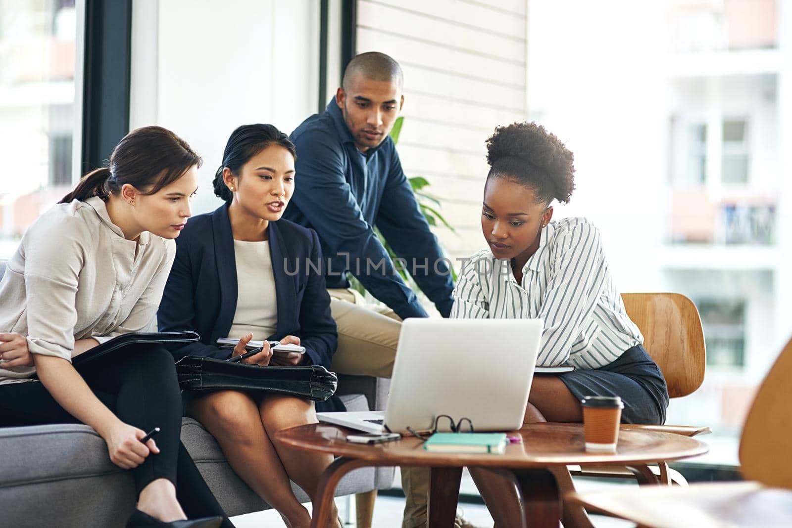 Shot of a group of businesspeople talking together over a laptop during a meeting.