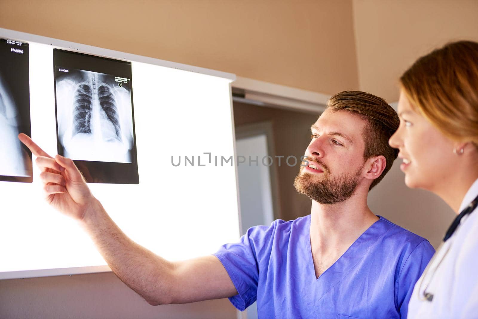 Shot of a young doctor and a male nurse examining an x-ray together.
