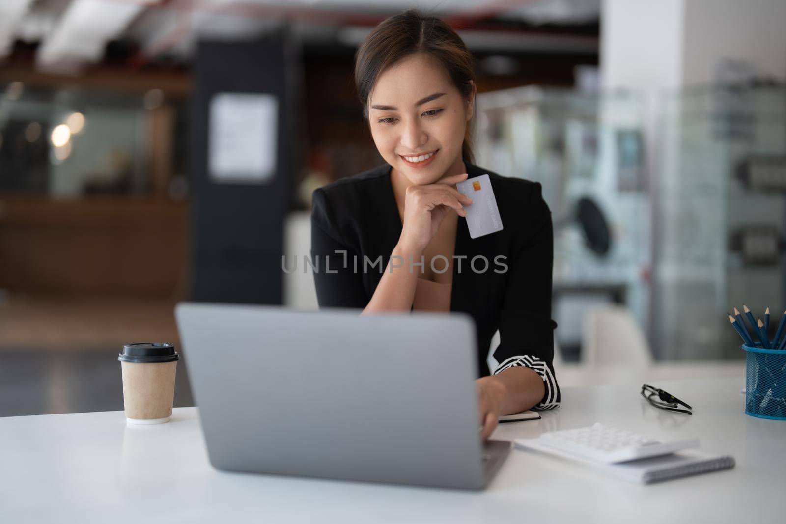 Asian girl making online payment using laptop and credit card for shopping at home.