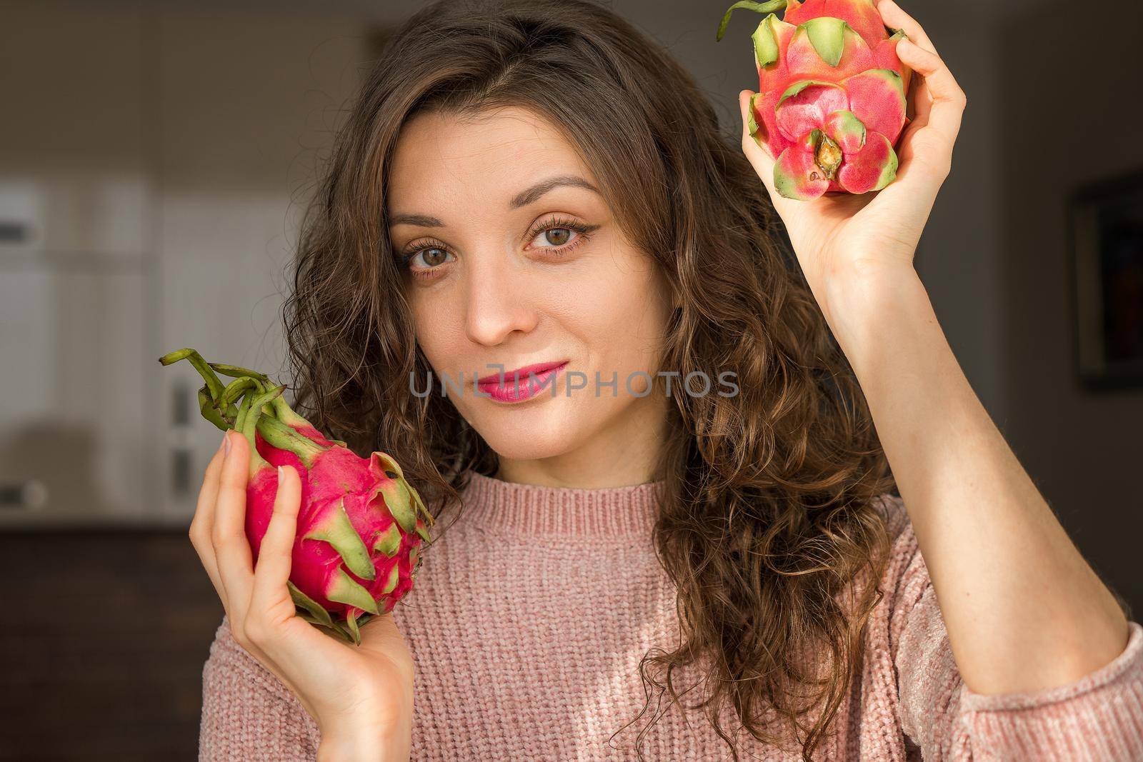 Young girl is holding two fresh ripe organic dragon fruits or pitaya, pitahaya. Exotic fruits, healthy eating concept by balinska_lv