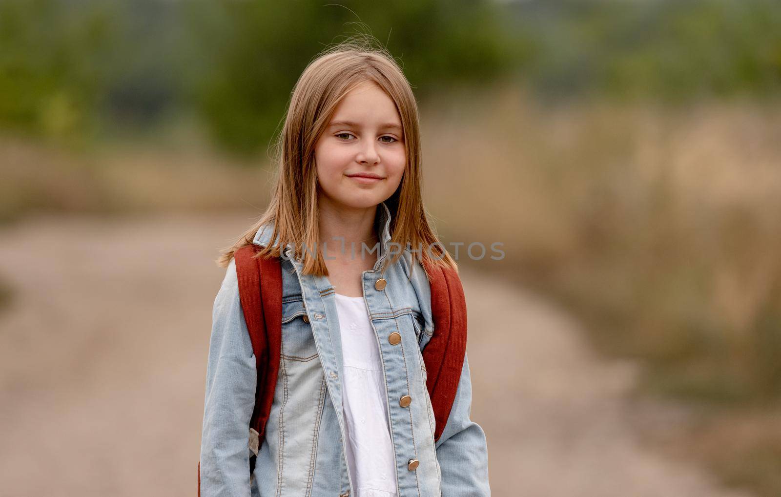 School girl with backpack in the field. Portrait of preteen child kid at nature