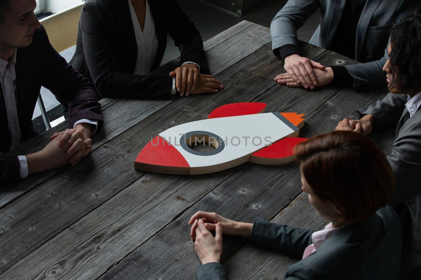 Team of business people with rocket as a sumbol of high risky goals targets success at meeting table