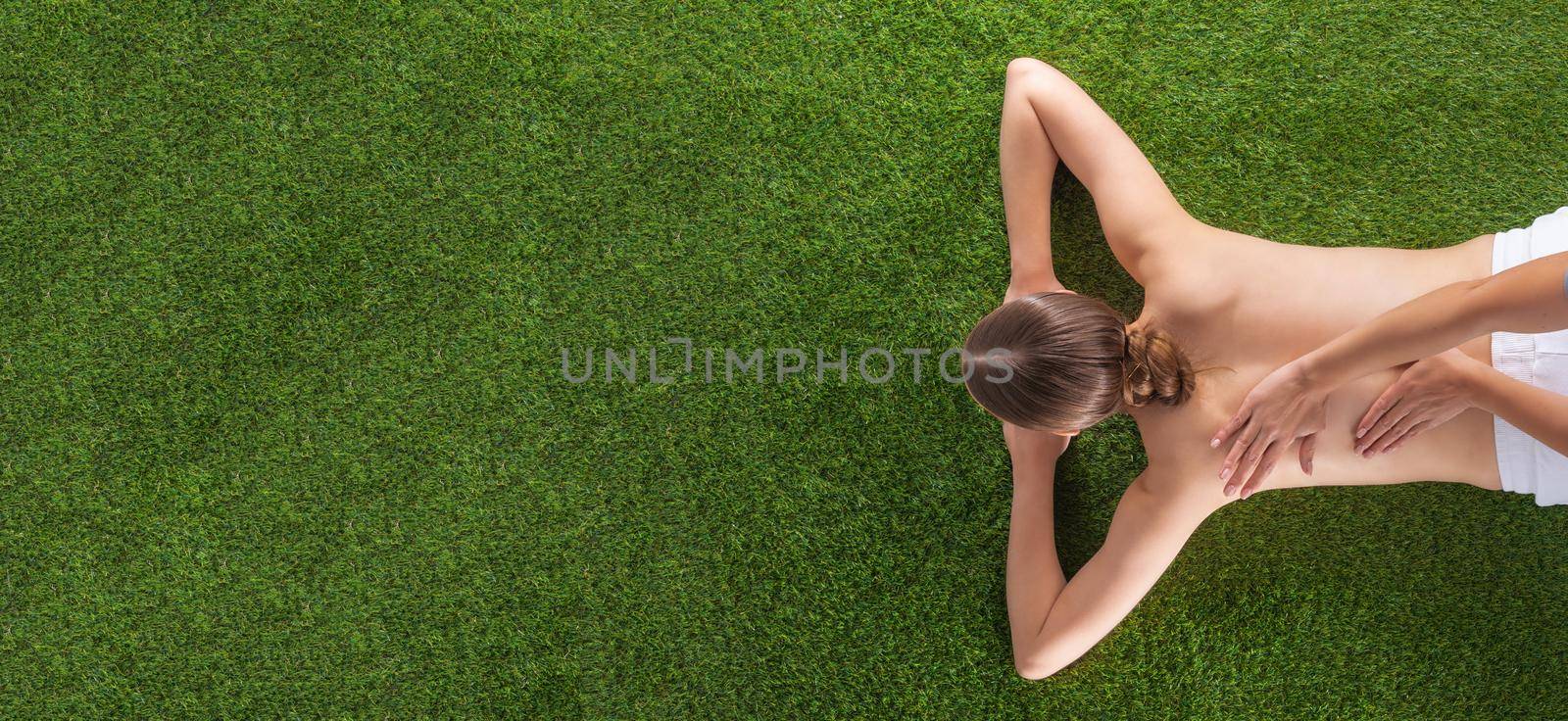 Natural body care concept, woman at spa massage lying on grass, top view, copy space for text content