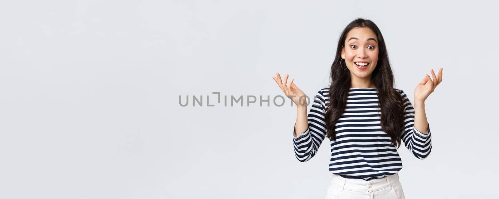 Lifestyle, beauty and fashion, people emotions concept. Surprised and amazed happy smiling asian woman find out perfect news, raise hands up astonished, congratulating or praising friend.