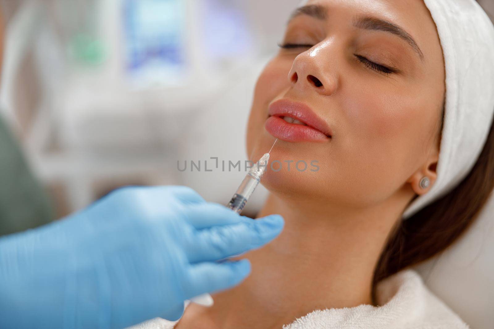 Attractive young woman getting rejuvenating injections in lips at beauty salon by Yaroslav_astakhov