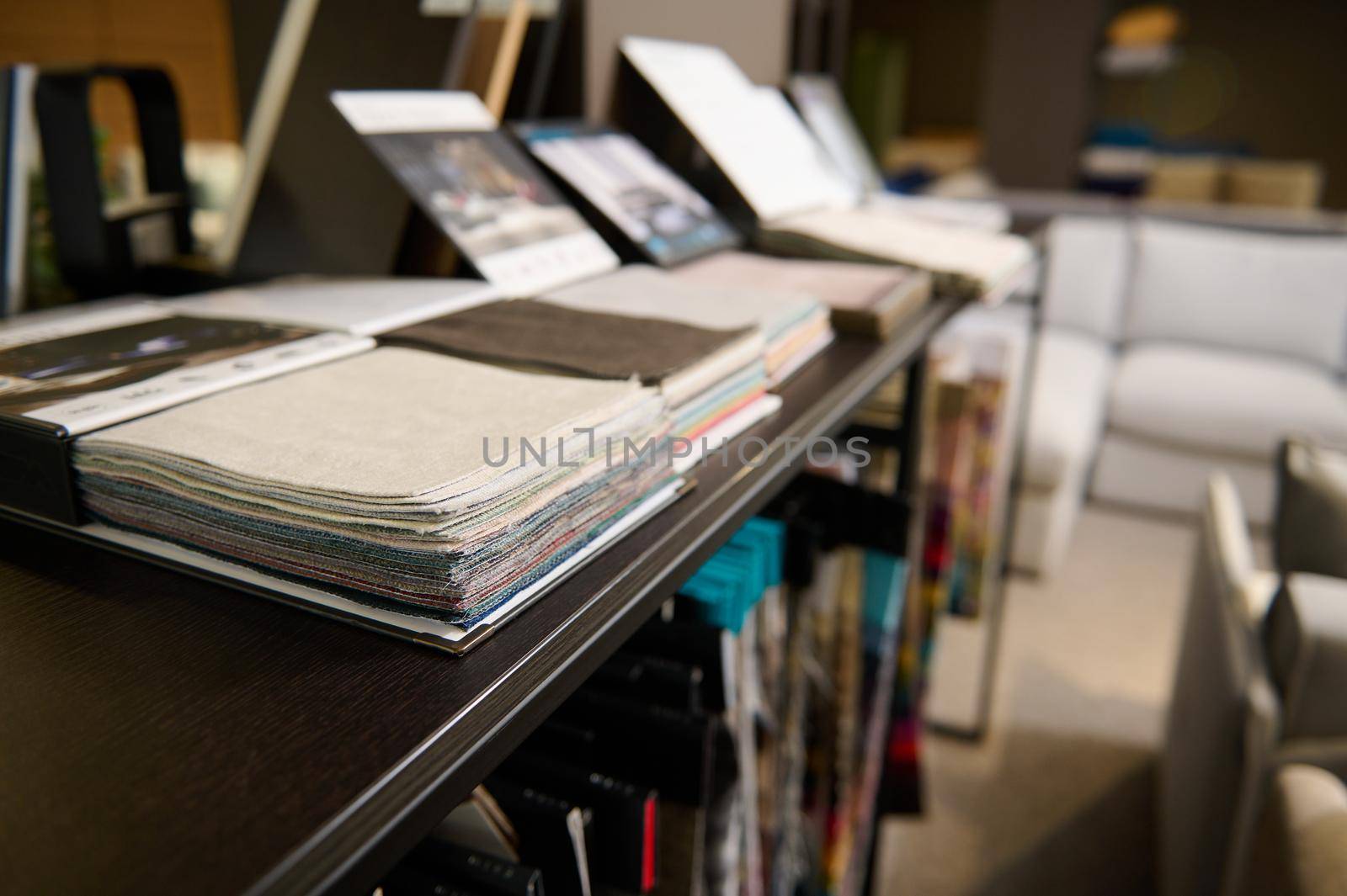 Samples of fabrics of different quality and category for furniture upholstery in a modern spacious exhibition hall, showroom of a furniture store