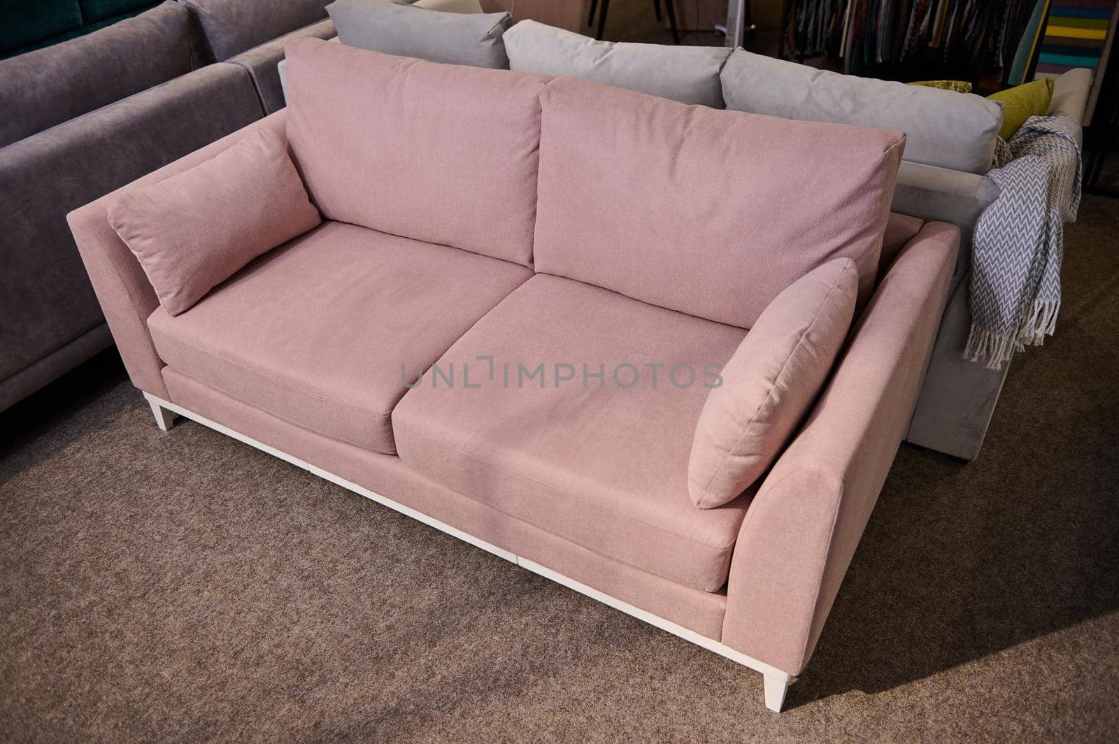 High angle view of a stylish pink settee with cushions in the showroom of upholstered furniture. Furniture store by artgf