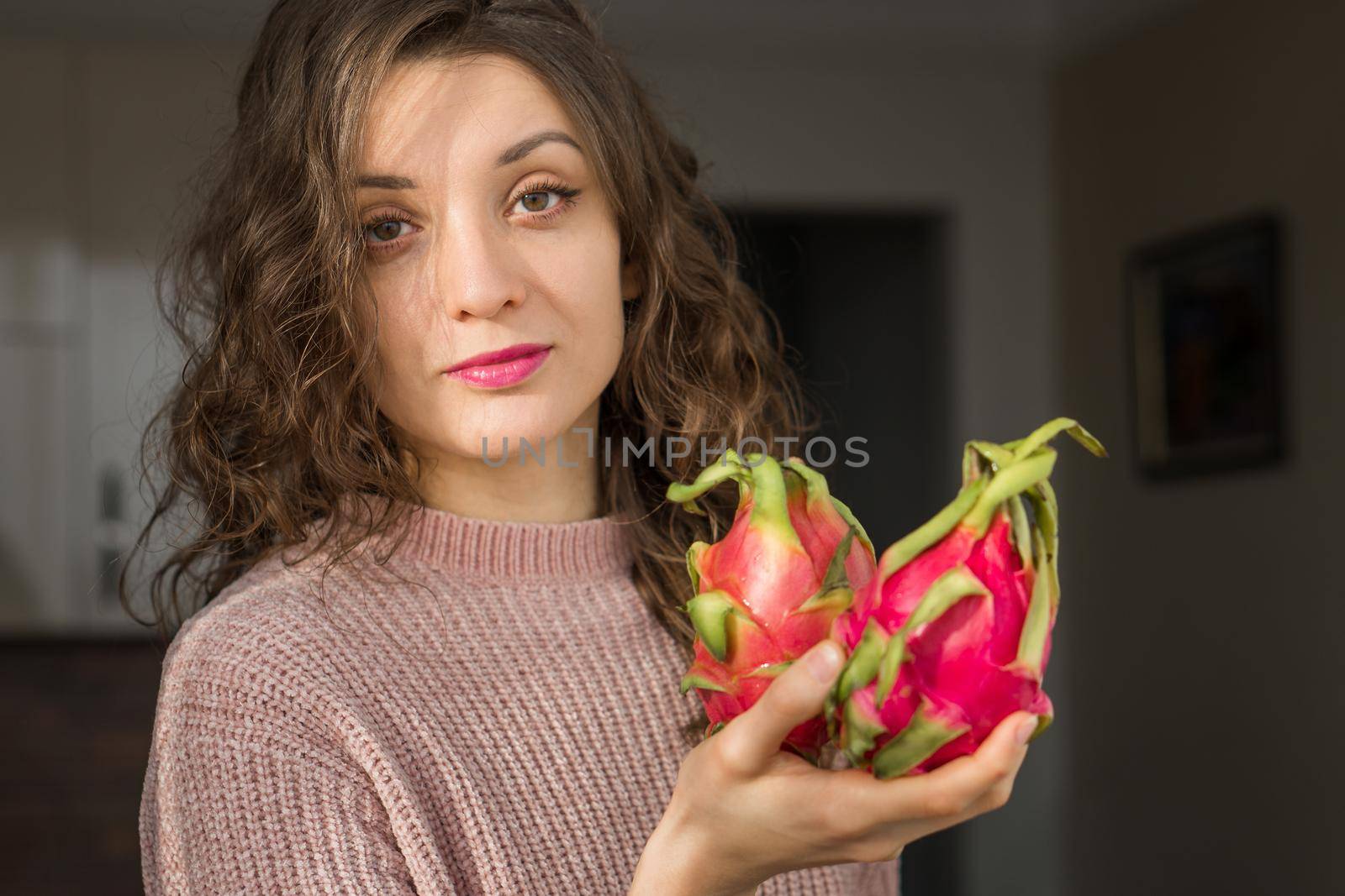 Young girl is holding two fresh ripe organic dragon fruits or pitaya, pitahaya. Exotic fruits, healthy eating concept by balinska_lv