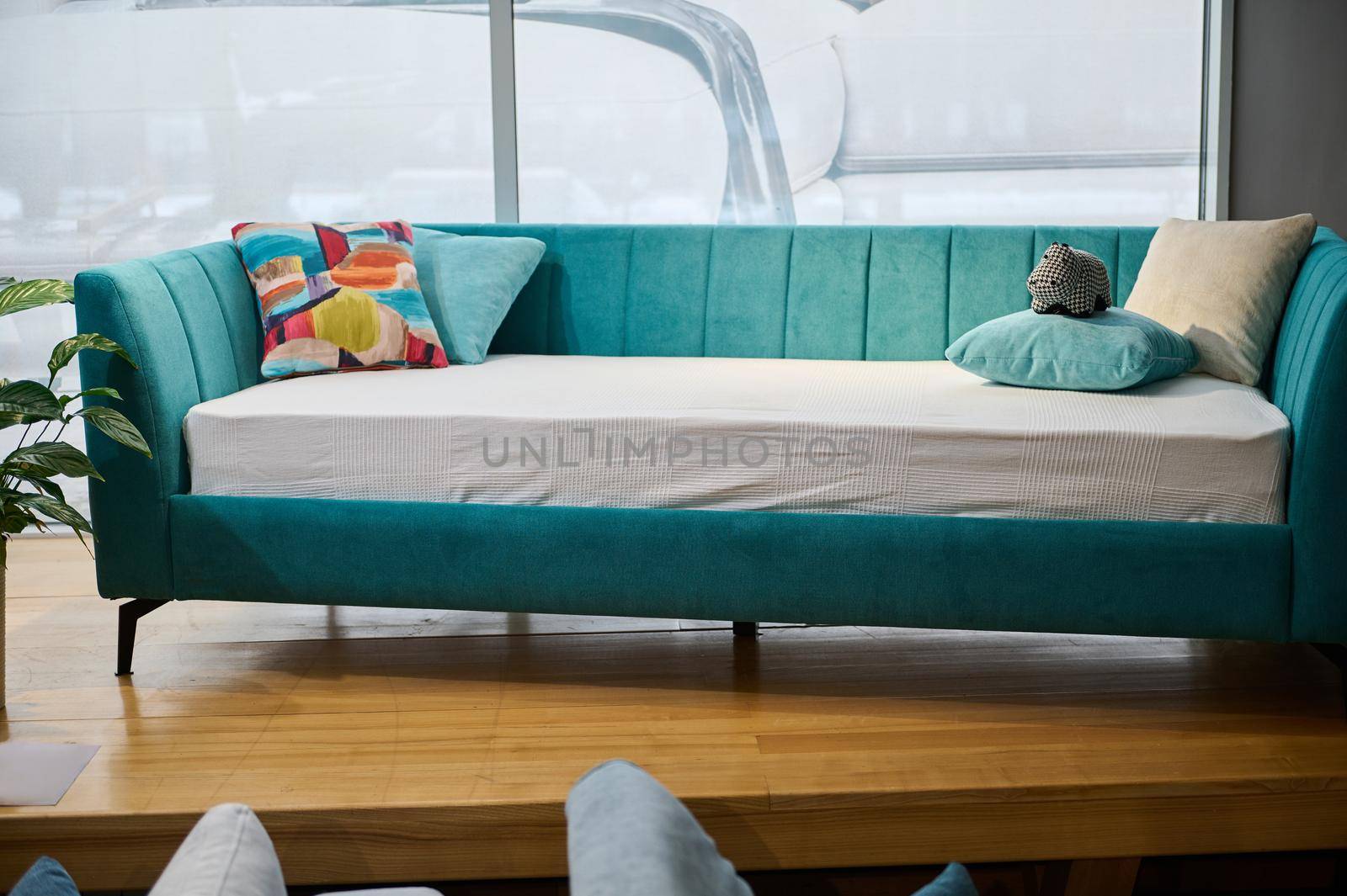 Modern beautiful stylish and minimalist children's sofa bed with soft bright turquoise velour fabric, displayed for sale in the furniture store showroom