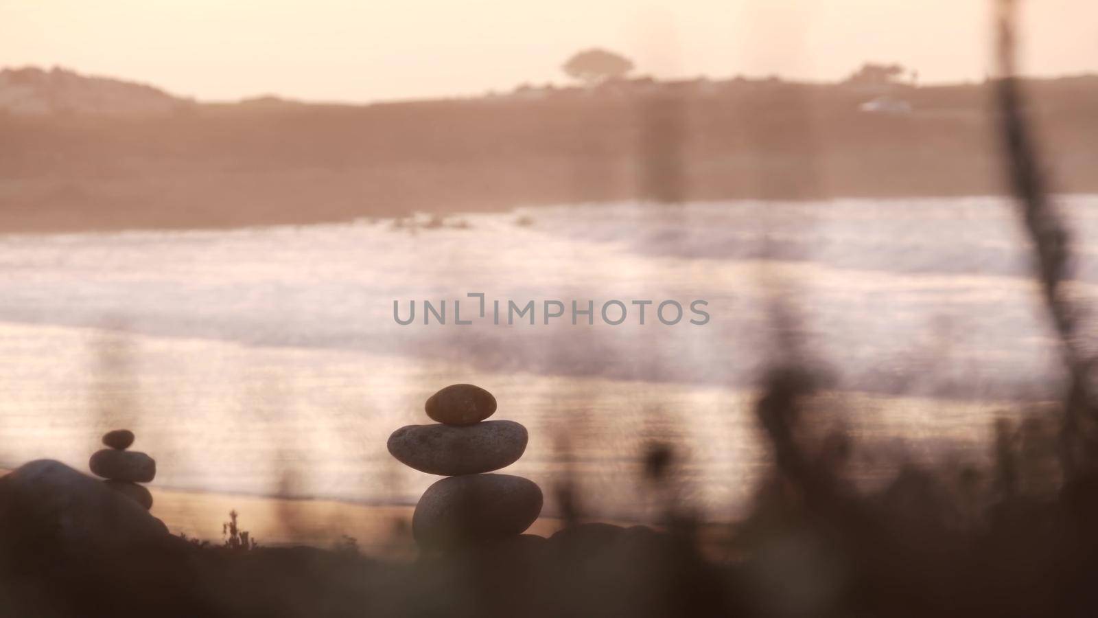 Rock balancing on pebble beach. Pyramid stacks of stones, ocean coast, sea water by DogoraSun