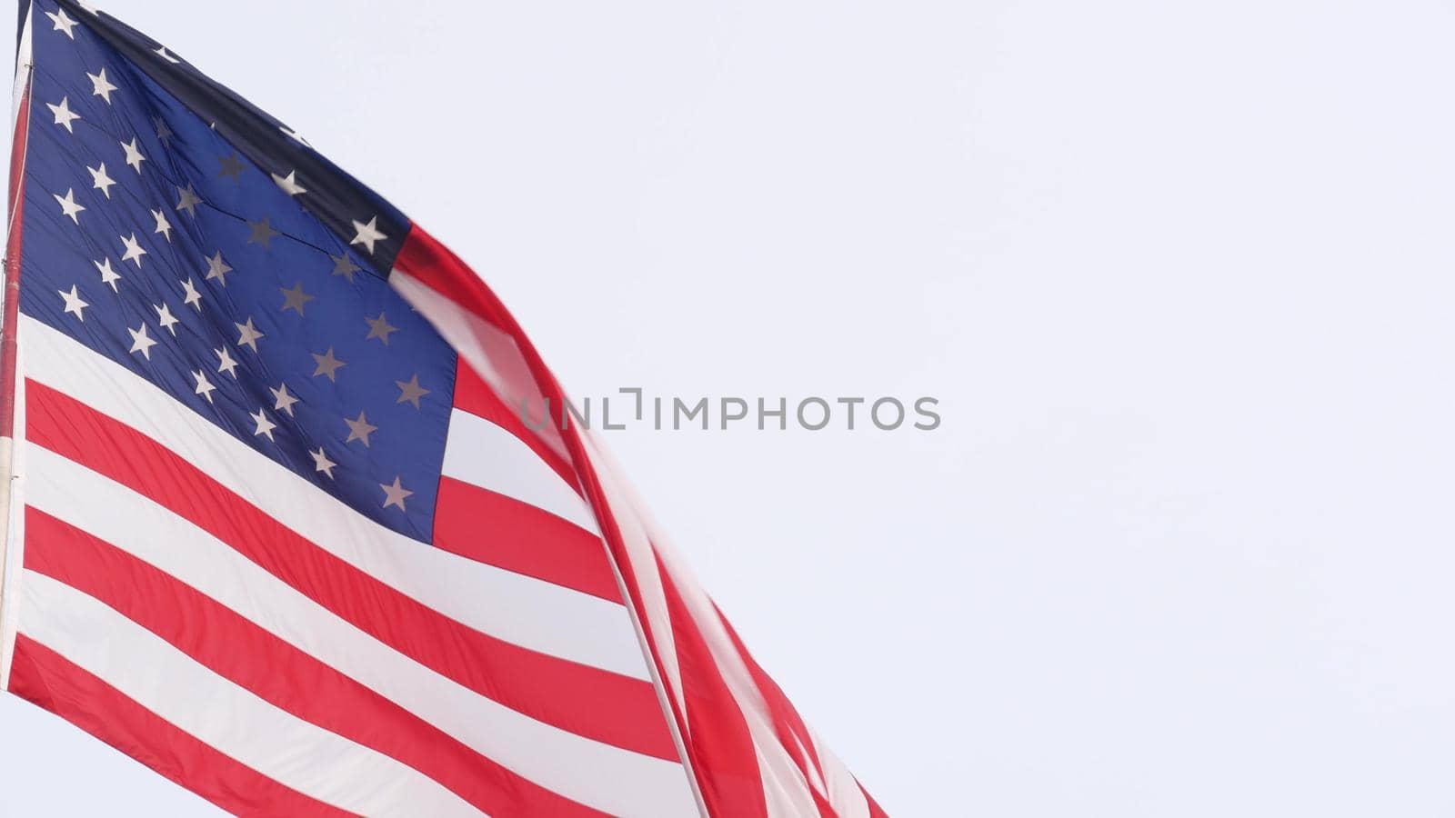 American flag waving in wind, USA. National symbol waves in breeze on flagpole. Real Old Glory Star Spangled Banner as concept of independence, liberty, democracy, patriotism. Background for 4th July.
