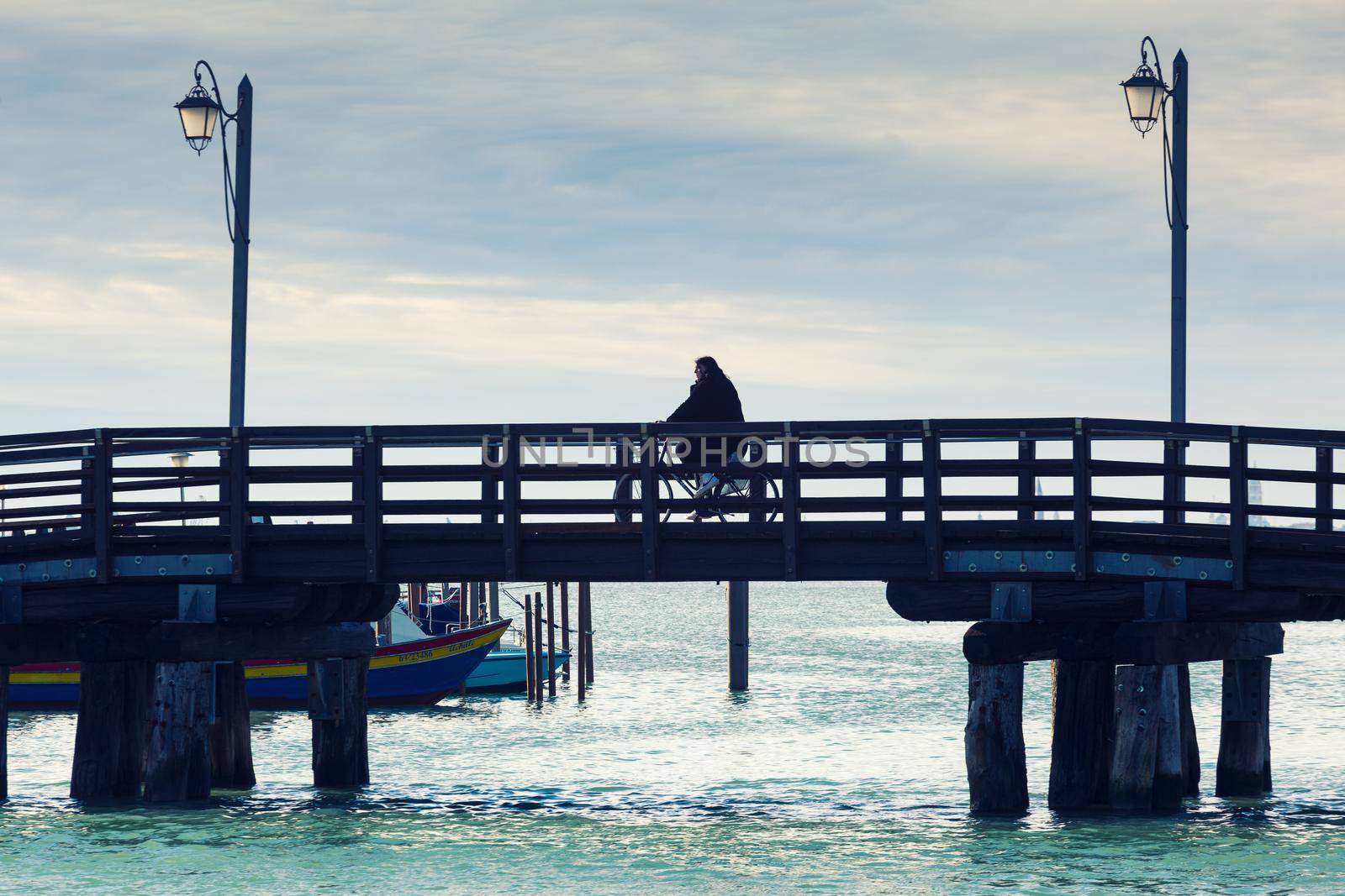 Mazzorbo, Italy - January, 06: Woman riding a bike on the Mazzorbo wooden bridge on January 06, 2022