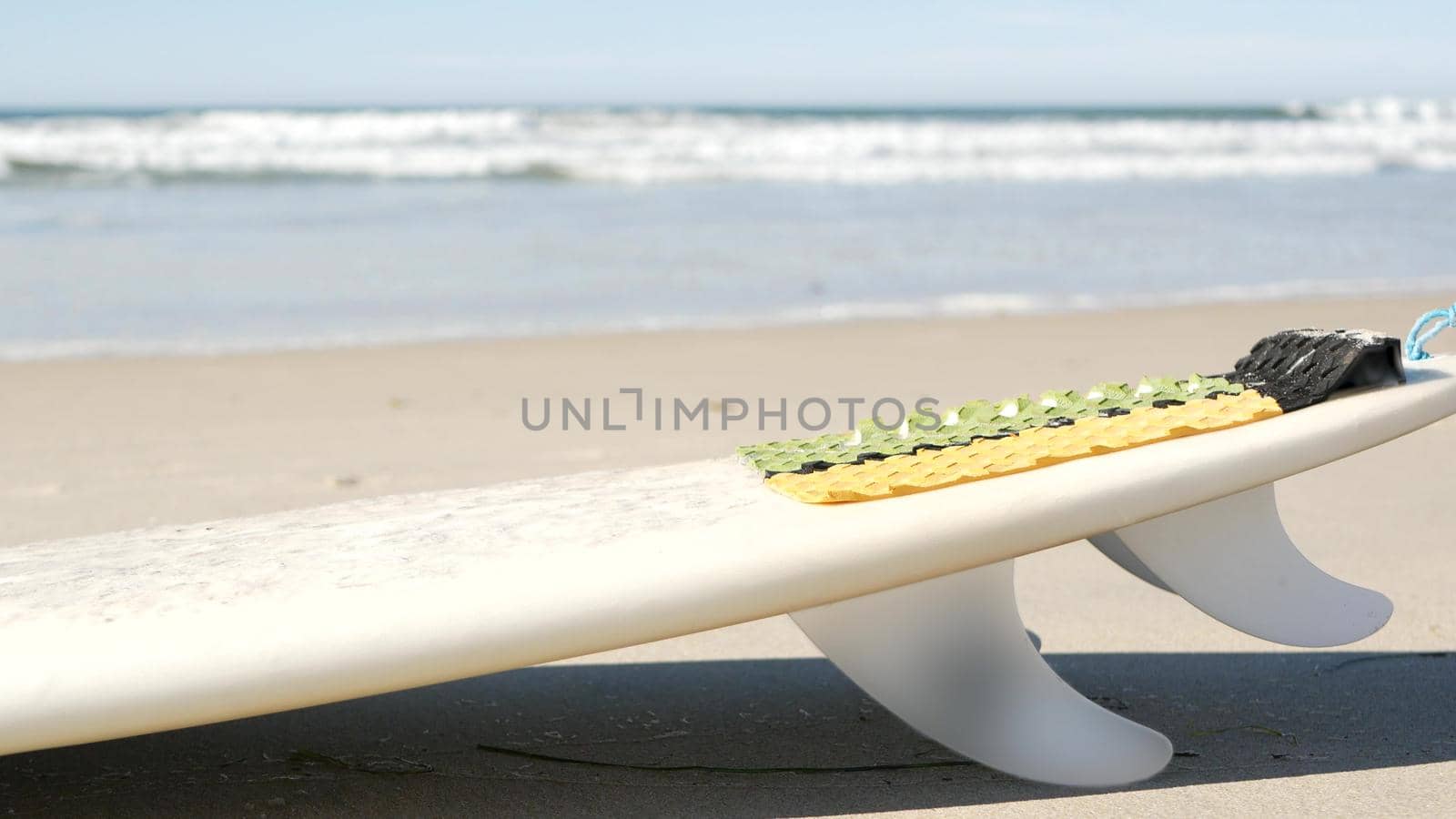 Surfboard for surfing lying on beach sand, California coast, USA. Ocean waves and white surf board or paddleboard. Longboard or sup for watersport recreation by sea water. Seamless looped cinemagraph.