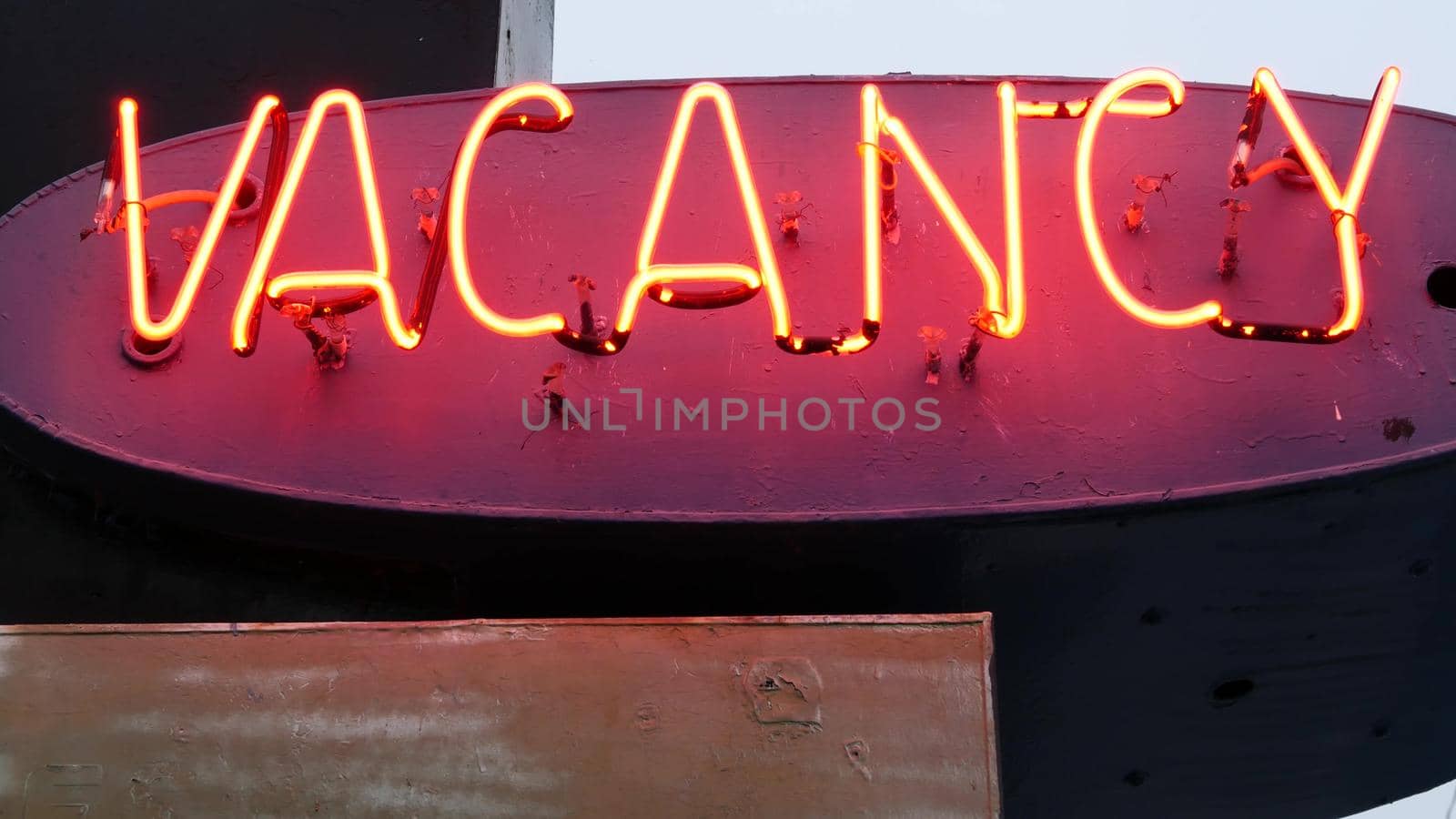 Red neon sign Vacancy glowing, motel or hotel on road in California USA. Illuminated text about lodging during road trip. Tourism or traveling in America.