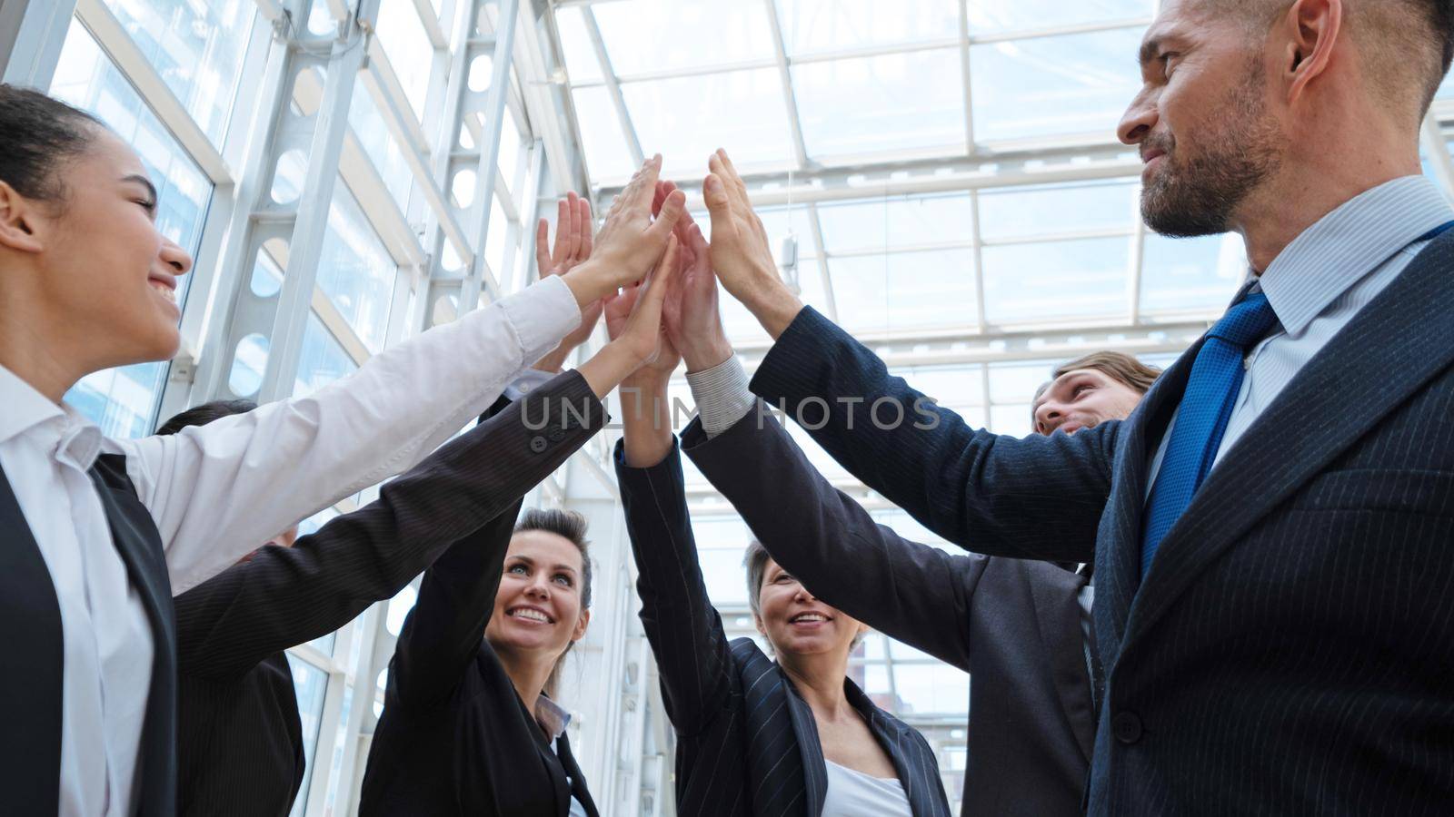 Happy successful multiracial business team giving a high fives gesture as they laugh and cheer their success