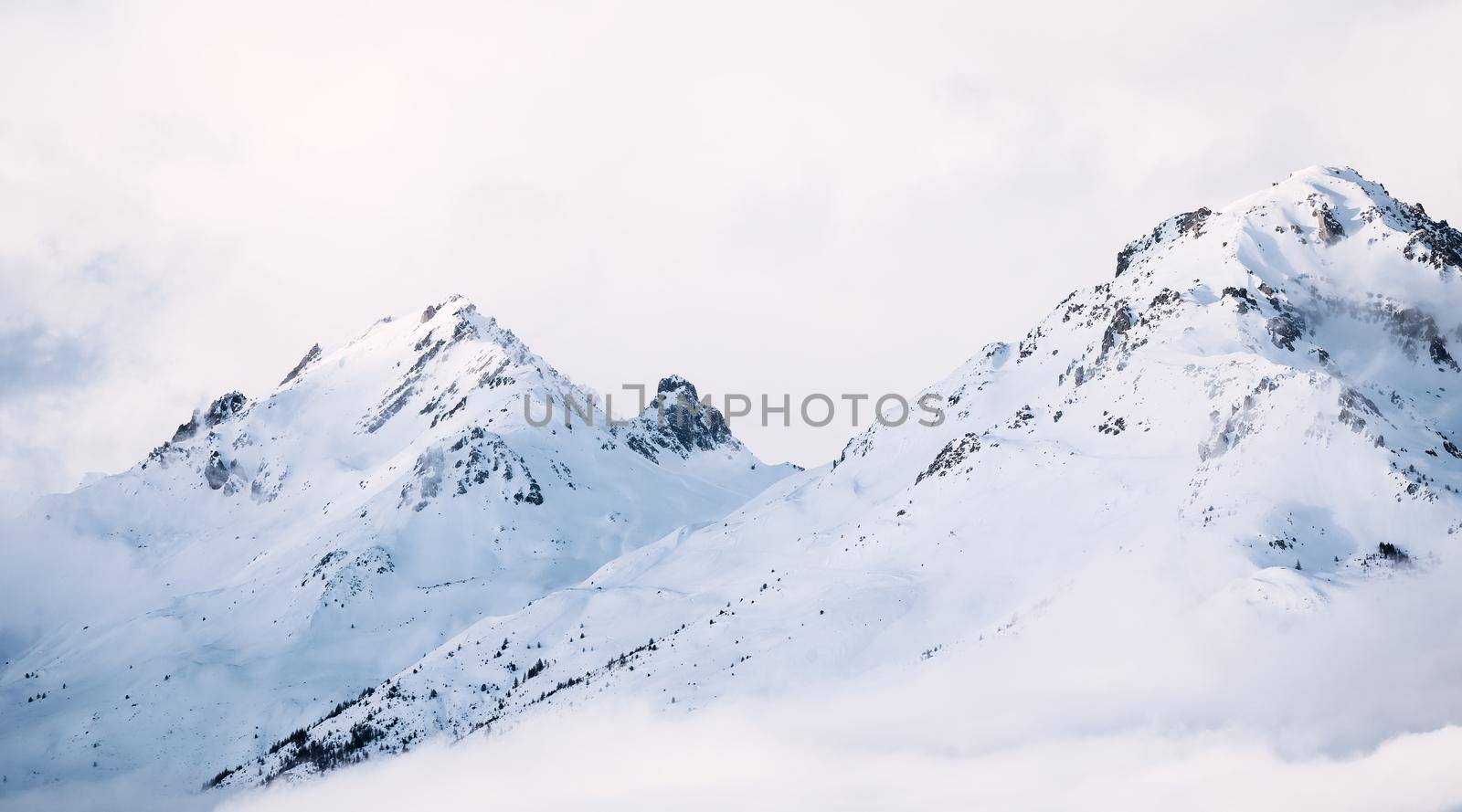 Panoramic view of mountains near Brianson, Serre Chevalier resort, France. Foggy winter mountain landscape. Ski resort landscape. Snowy mountains. Winter vacation. Misty morning in mountains