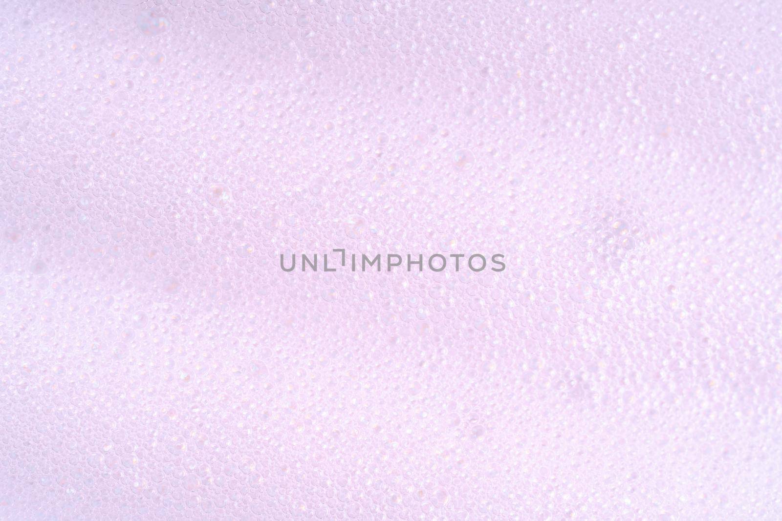 Purple laundry spume. Foam macro background with bubbles. Soapy surface closeup. Foamy cleansing skin care product texture from soap, detergent, shampoo by photolime