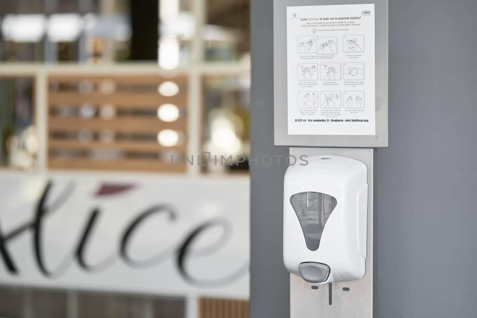 Hand sanitizer machine in public place near the wall at the entrance to shopping center. Automatic dispenser with alcohol gel sanitizer by photolime